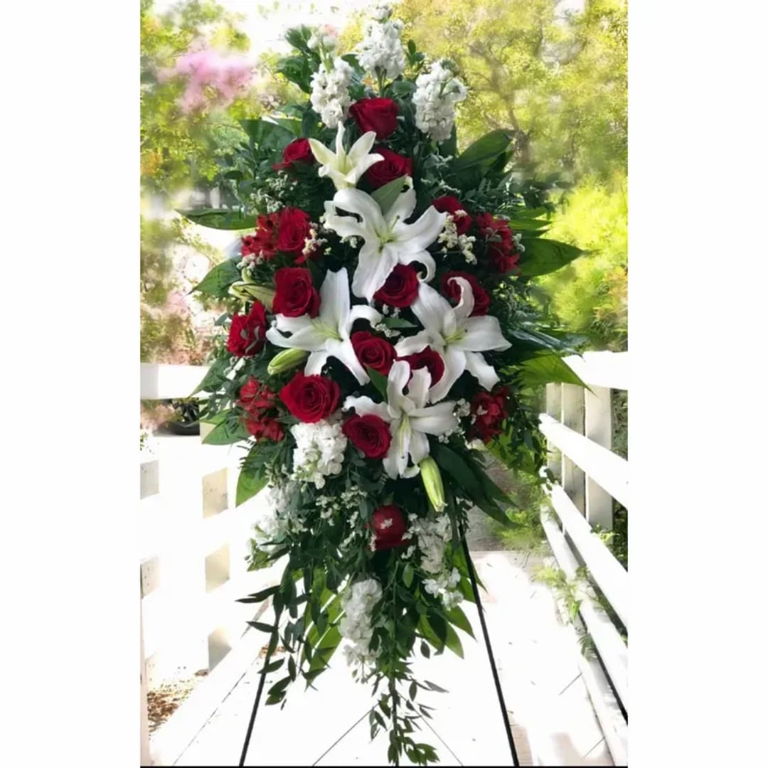 Standing floral spray with red roses and white lilies on a white easel