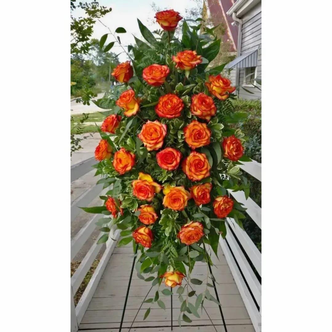 Tall standing spray of orange and yellow roses with greenery