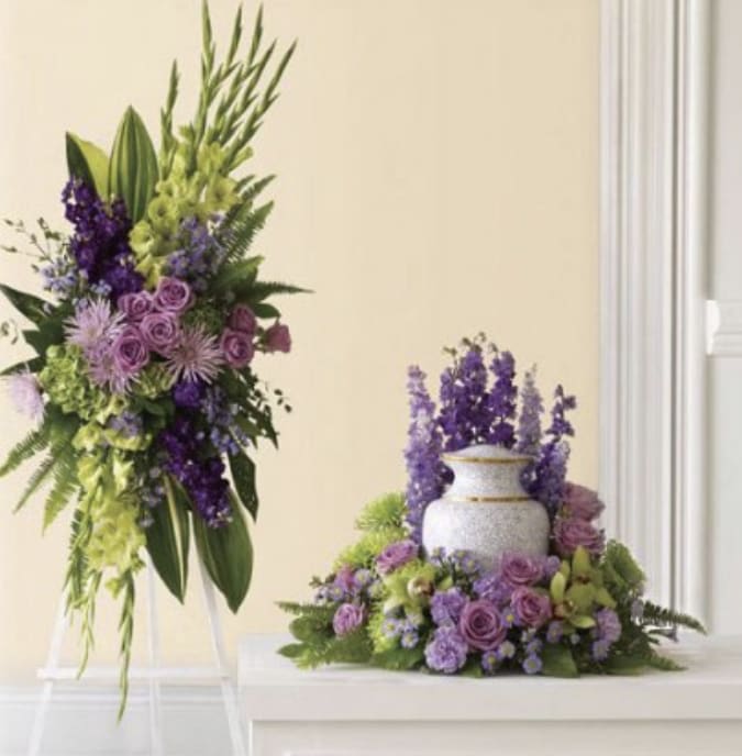 Purple and green floral arrangements with a white urn centerpiece