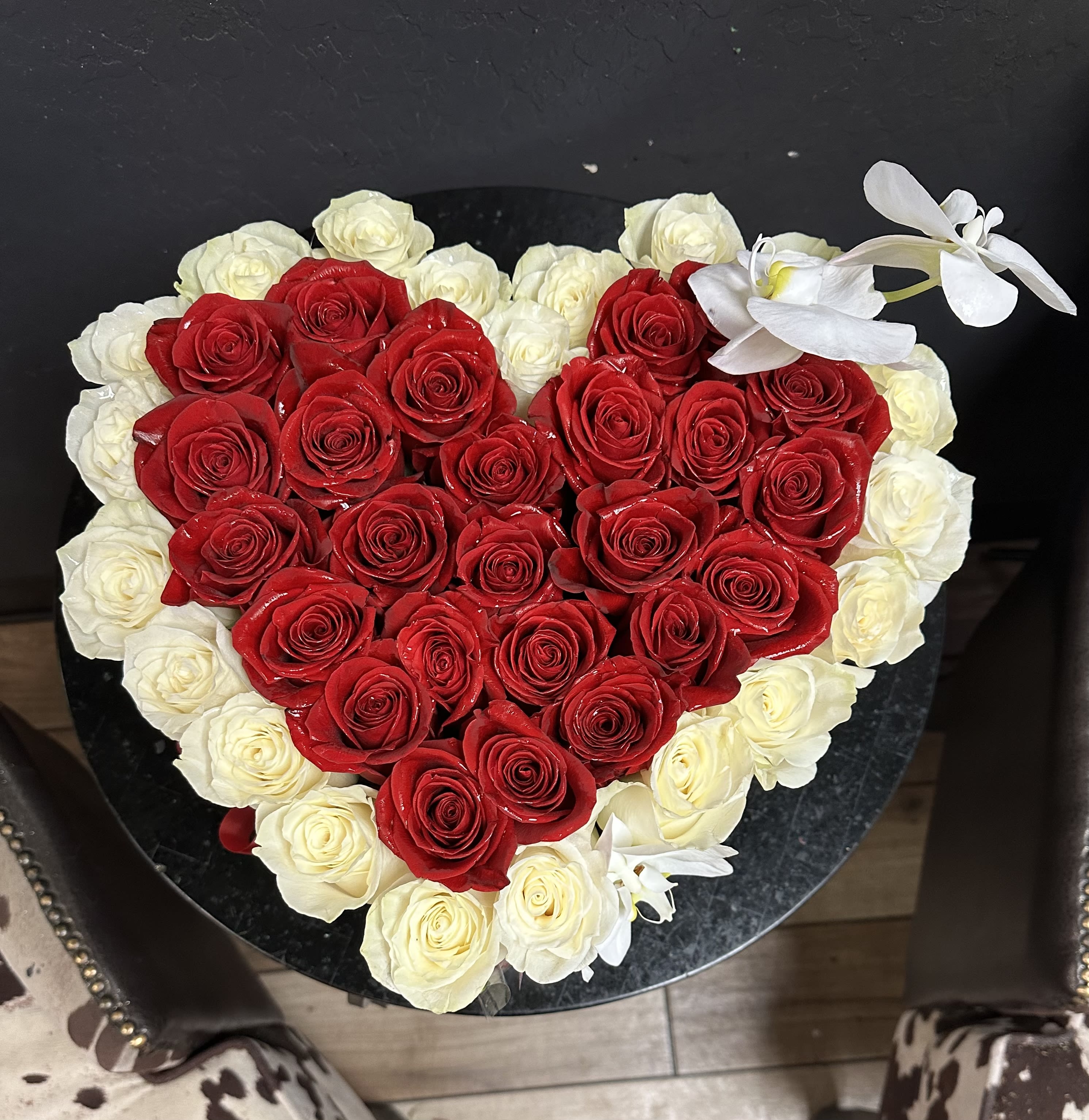 Heart-shaped arrangement of red and white roses with white orchids