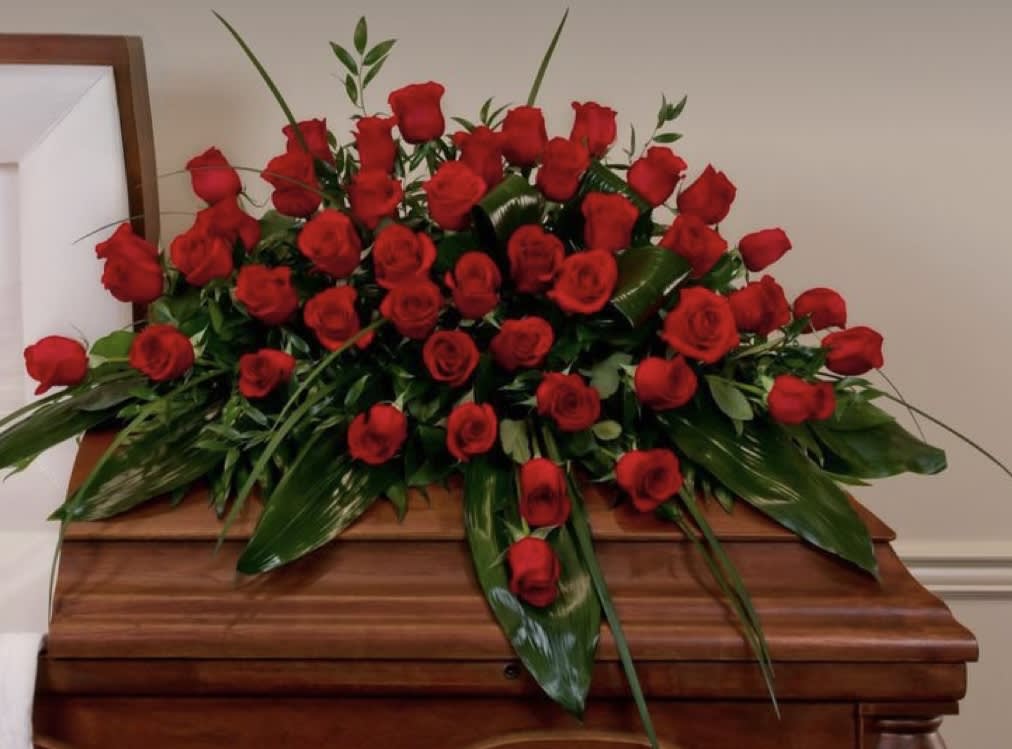Large arrangement of red roses on a wooden casket