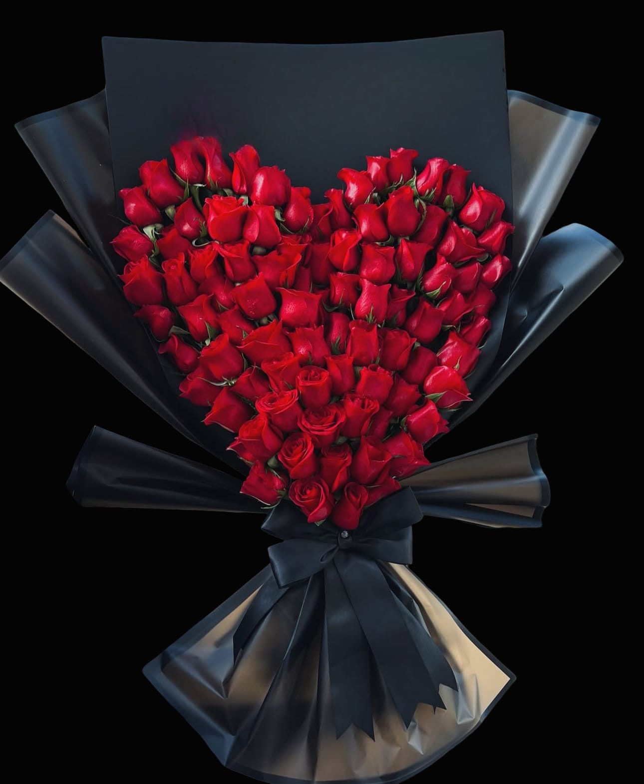 Heart-shaped bouquet of red roses wrapped in black paper