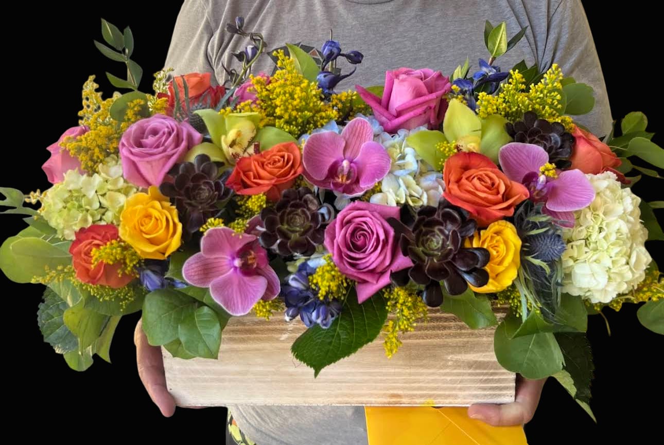 Colorful mixed bouquet in a wooden box with roses and orchids