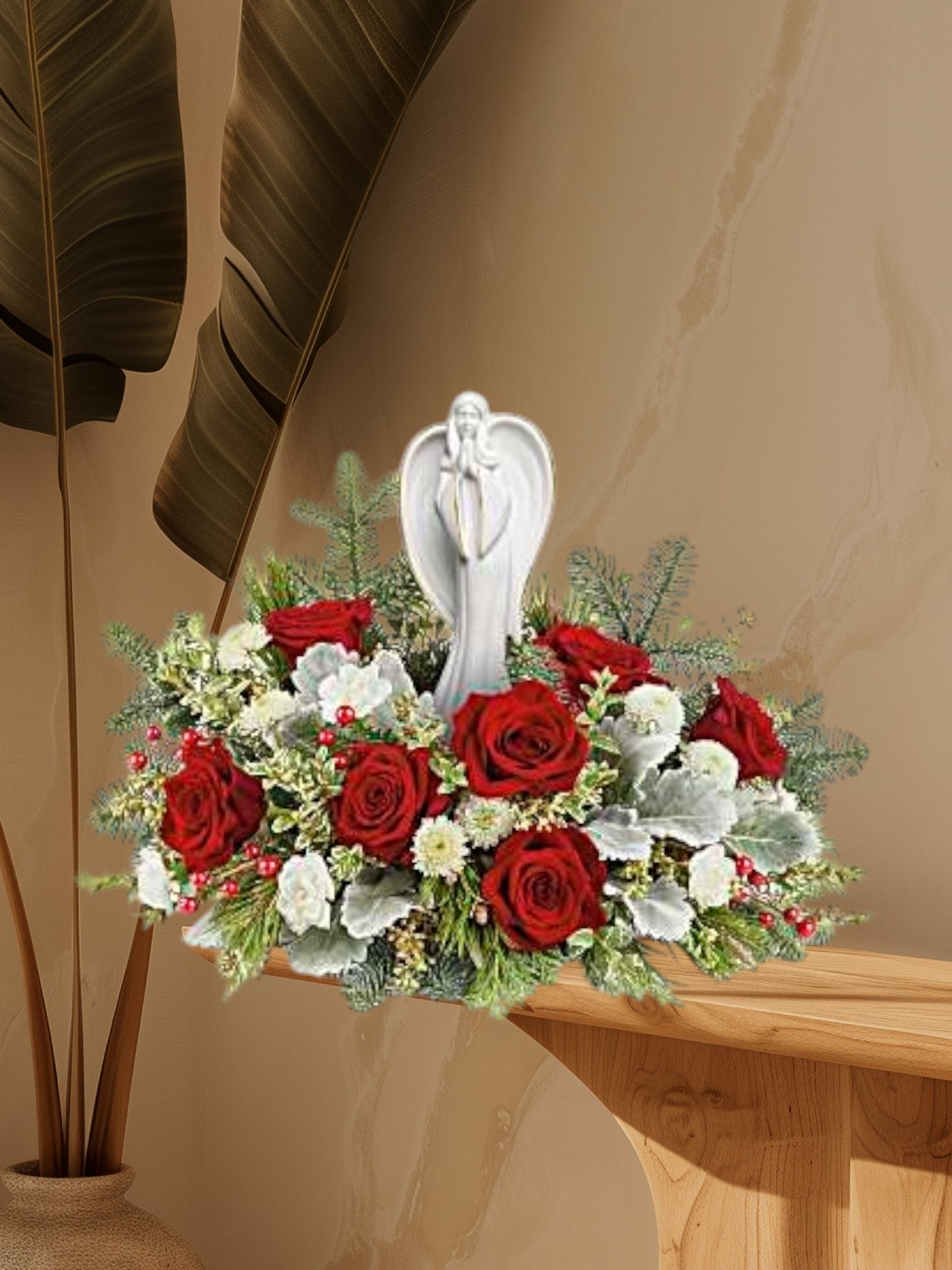 Red roses and white flowers arranged around a white angel figurine