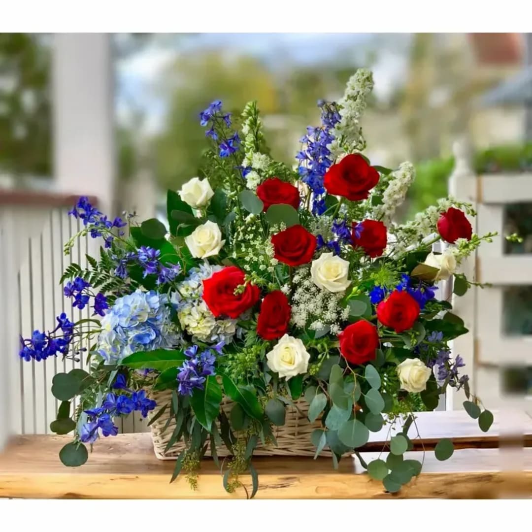 Basket arrangement of red and white roses with blue flowers