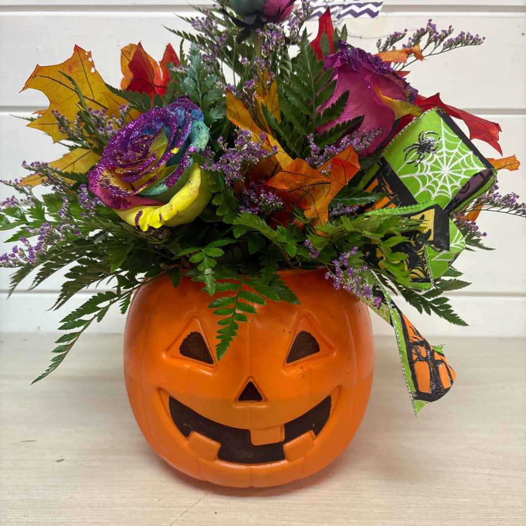 Halloween bouquet in a jack-o'-lantern container with a rainbow rose
