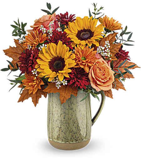 Teleflora's Harvest Season Bouquet - Like the autumn sun's warmth, this delightful sunflower bouquet is elegantly showcased in a food-safe stoneware pitcher adorned with a neutral green reactive glaze.