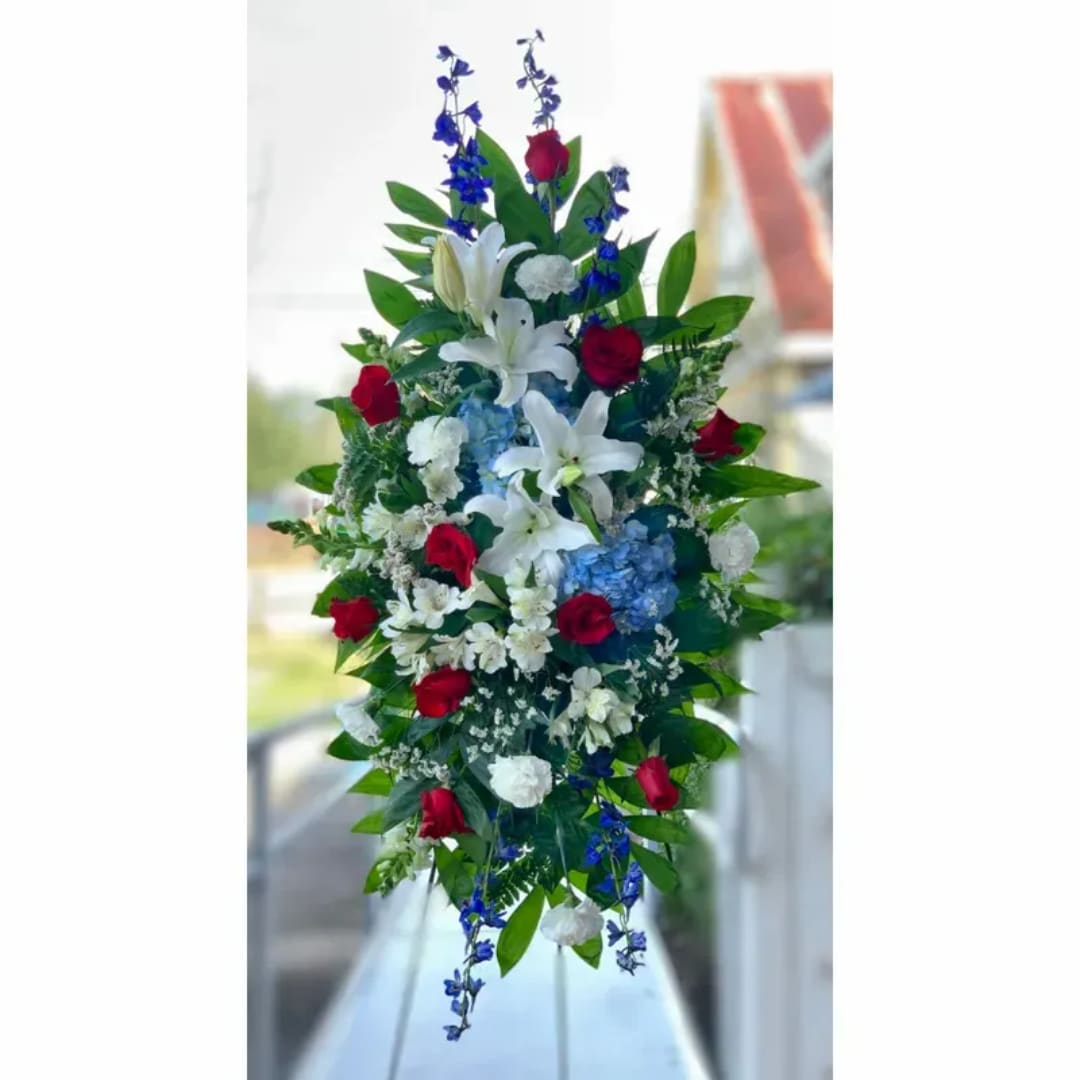 Tall floral arrangement with white lilies, red roses, and blue accents