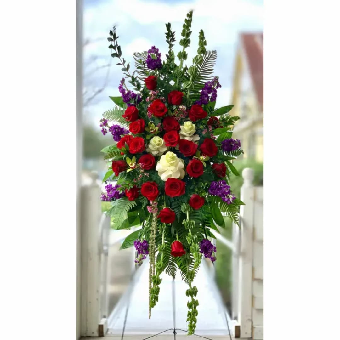 Tall standing arrangement of red and white roses with purple accents