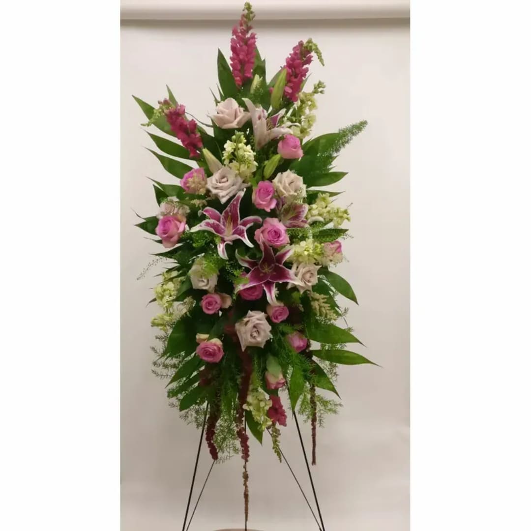 Tall standing floral spray with pink roses and lilies on a metal easel