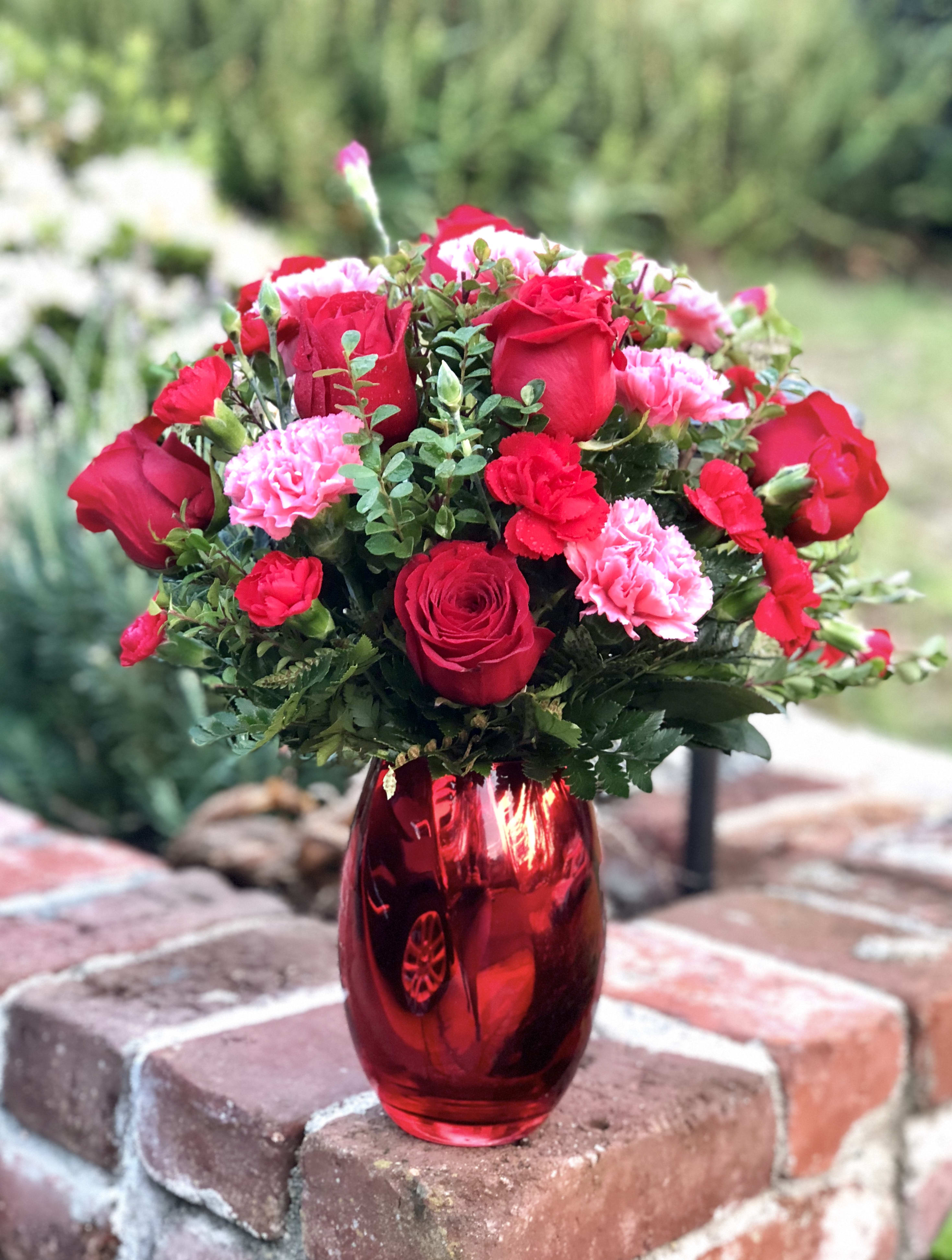 Red roses and pink carnations in a red glass vase
