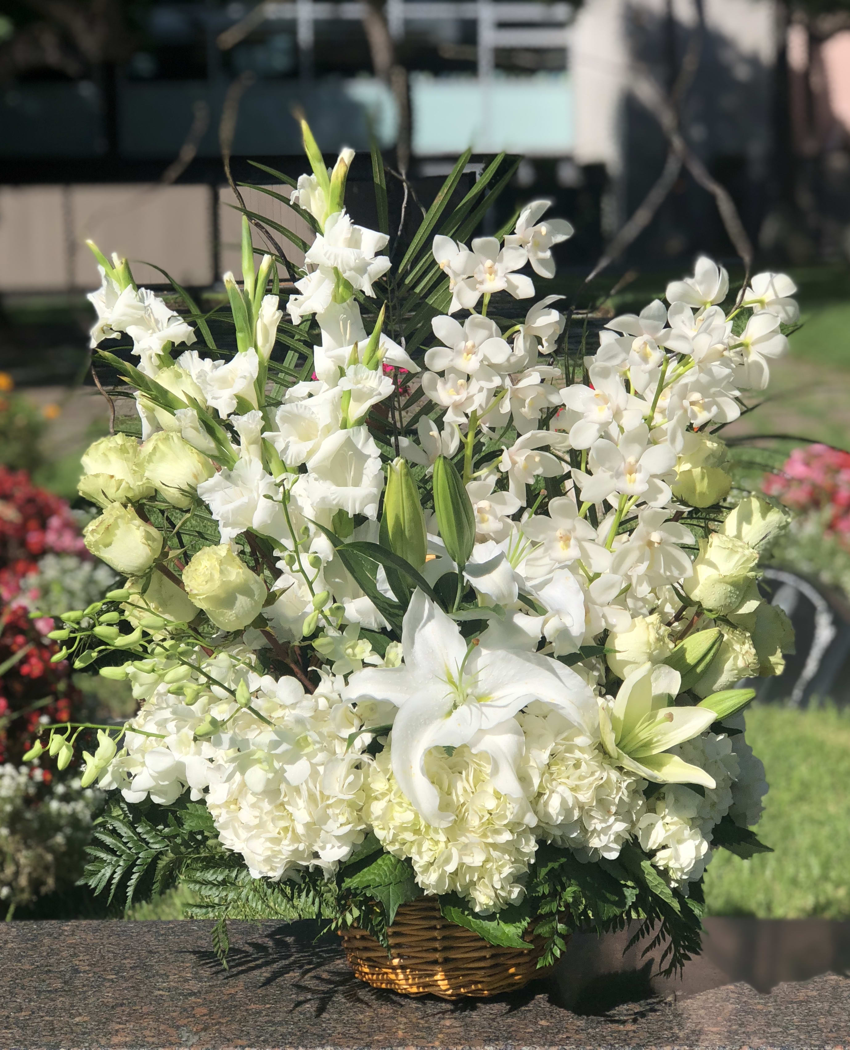 White lilies and orchids arranged in a wicker basket