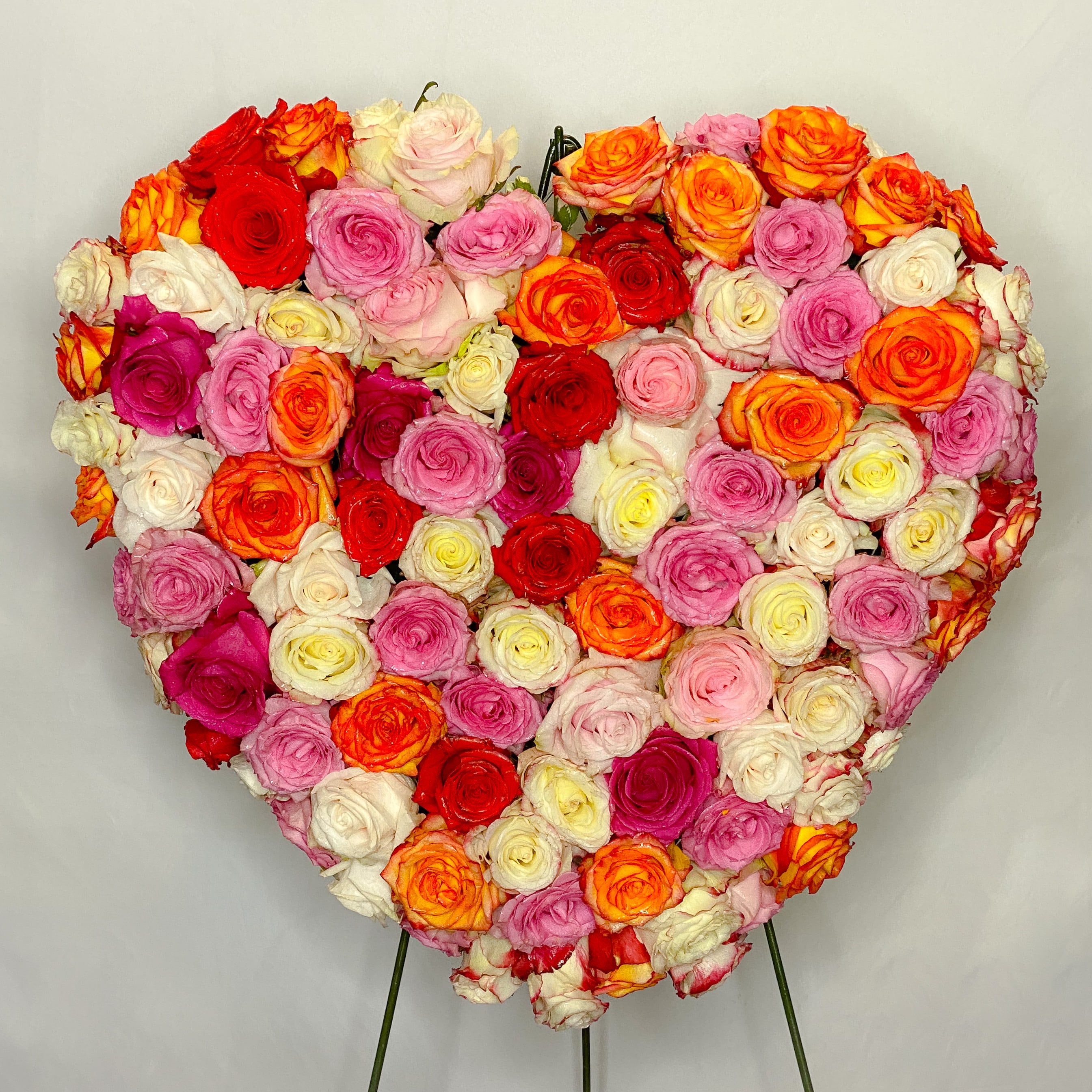Loving Heart Standing Spray - An all Ecuadorian red, pink, white and lavender roses arranged in this beautiful solid heart standing spray to express your deepest love and devotion. When all is said and done, only your heart will speak the words unspoken.  Approximately 22” D