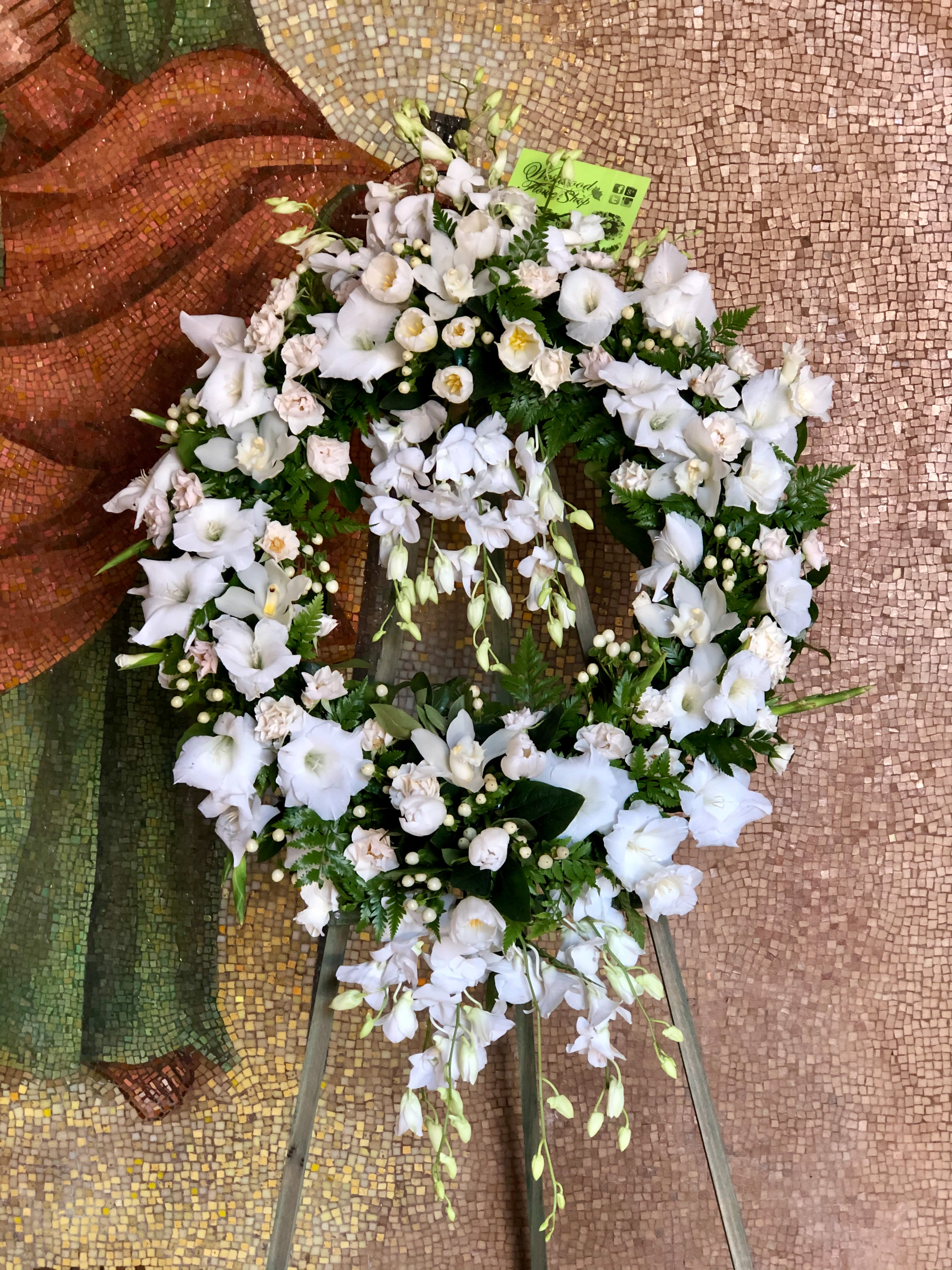 White floral wreath on a stand with trailing blooms