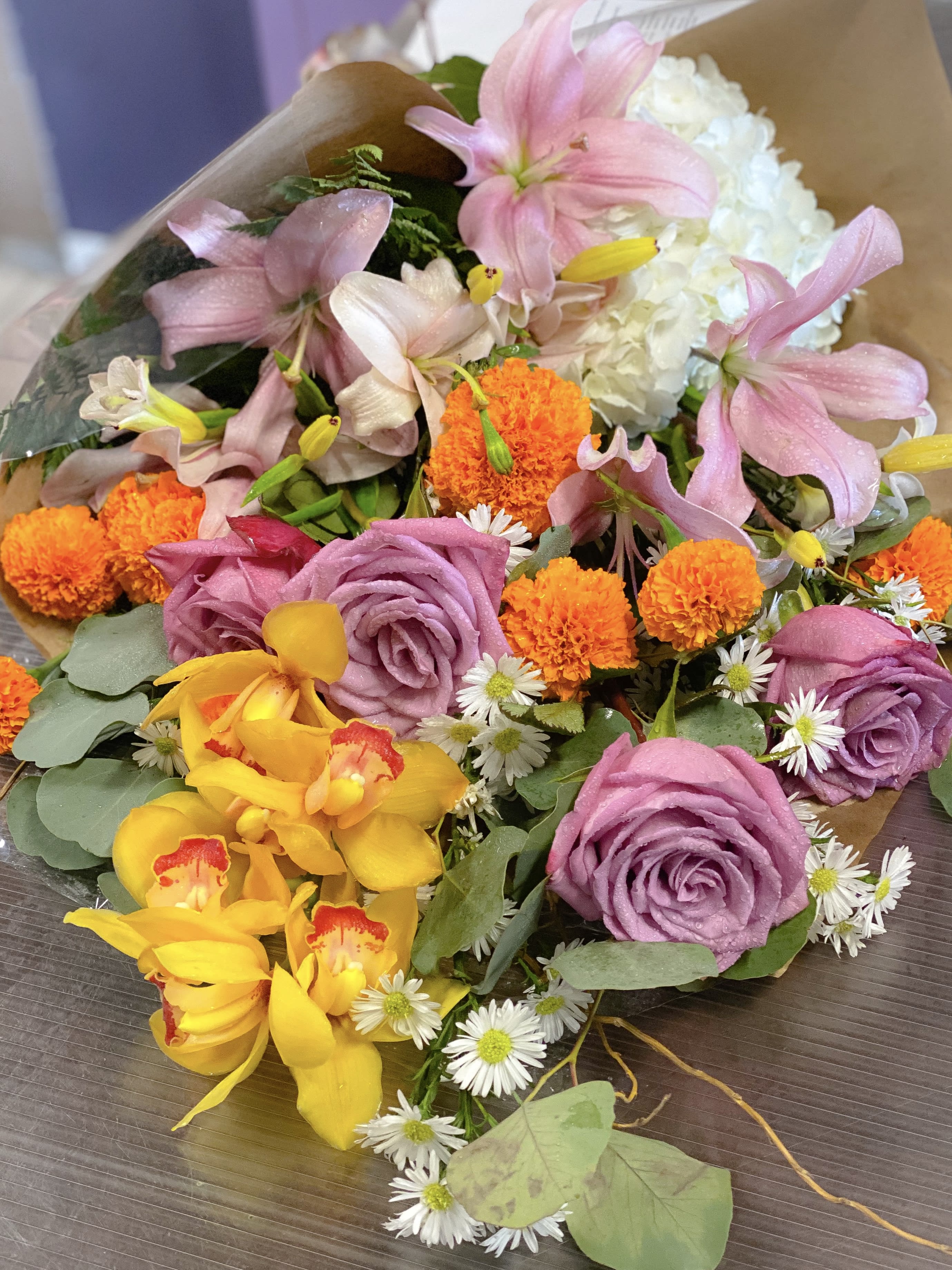 Bouquet of pink lilies, purple roses, and orange marigolds