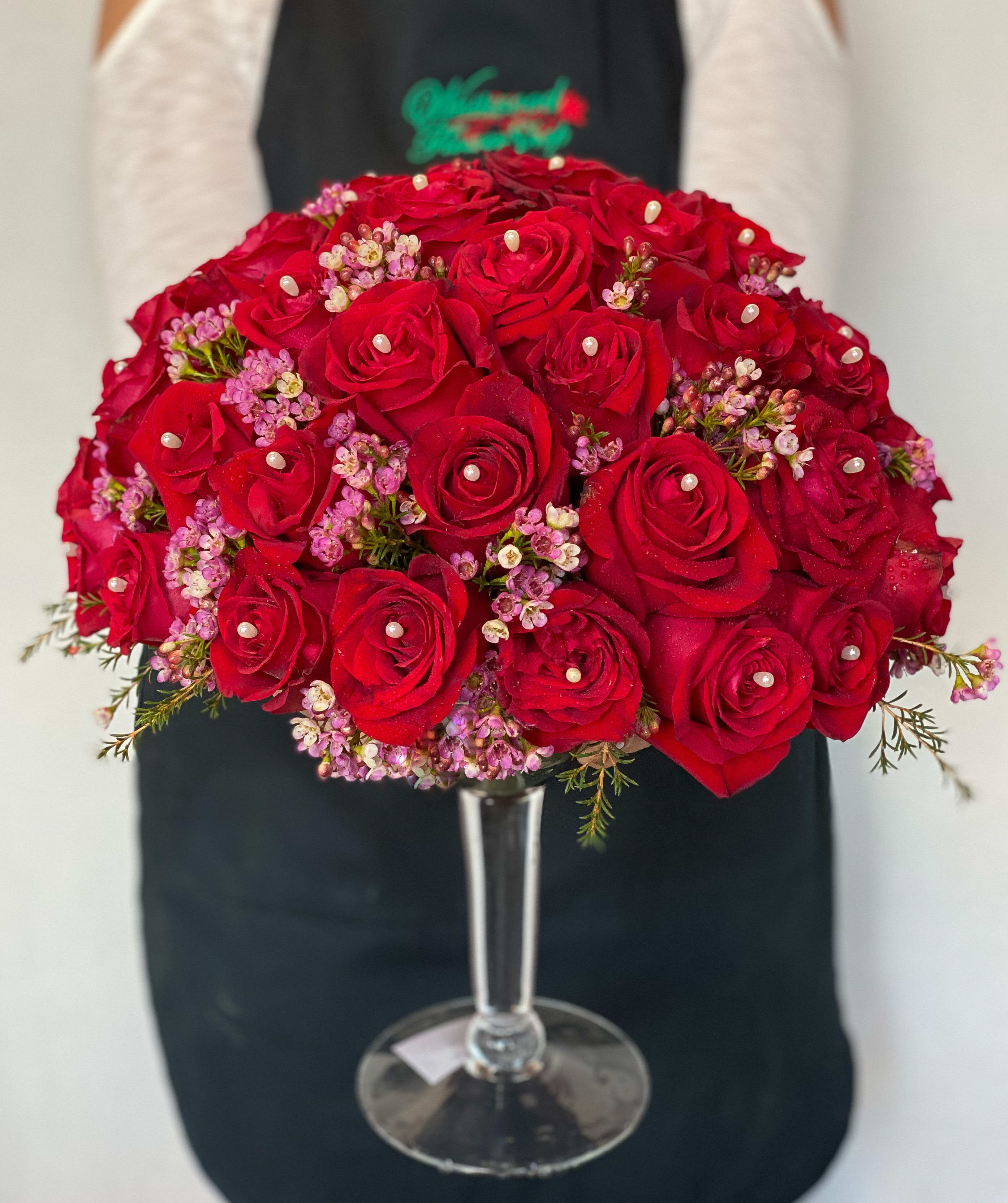 Red rose bouquet with pink filler flowers in a clear glass vase