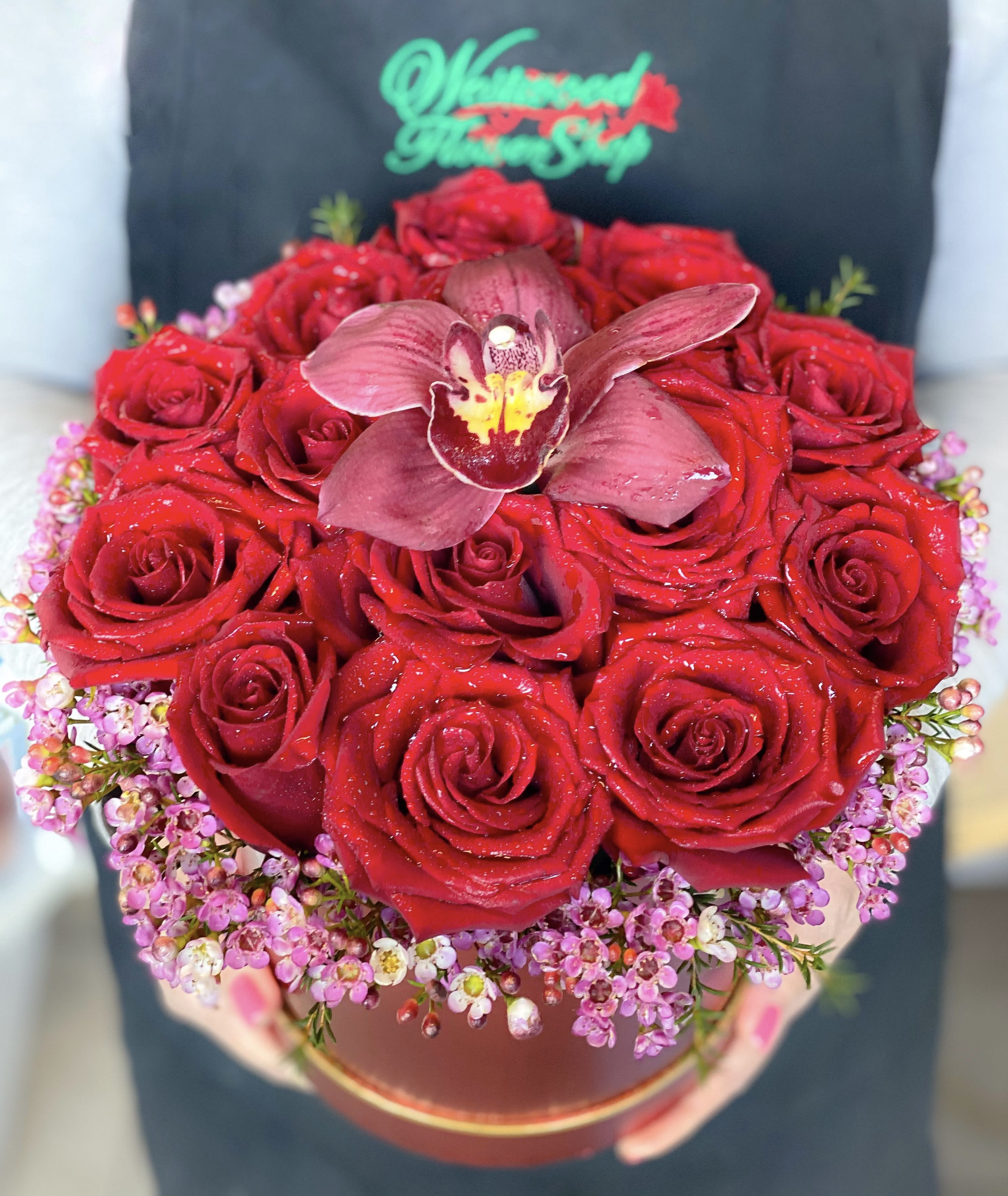 Red rose bouquet with a central orchid in a round box