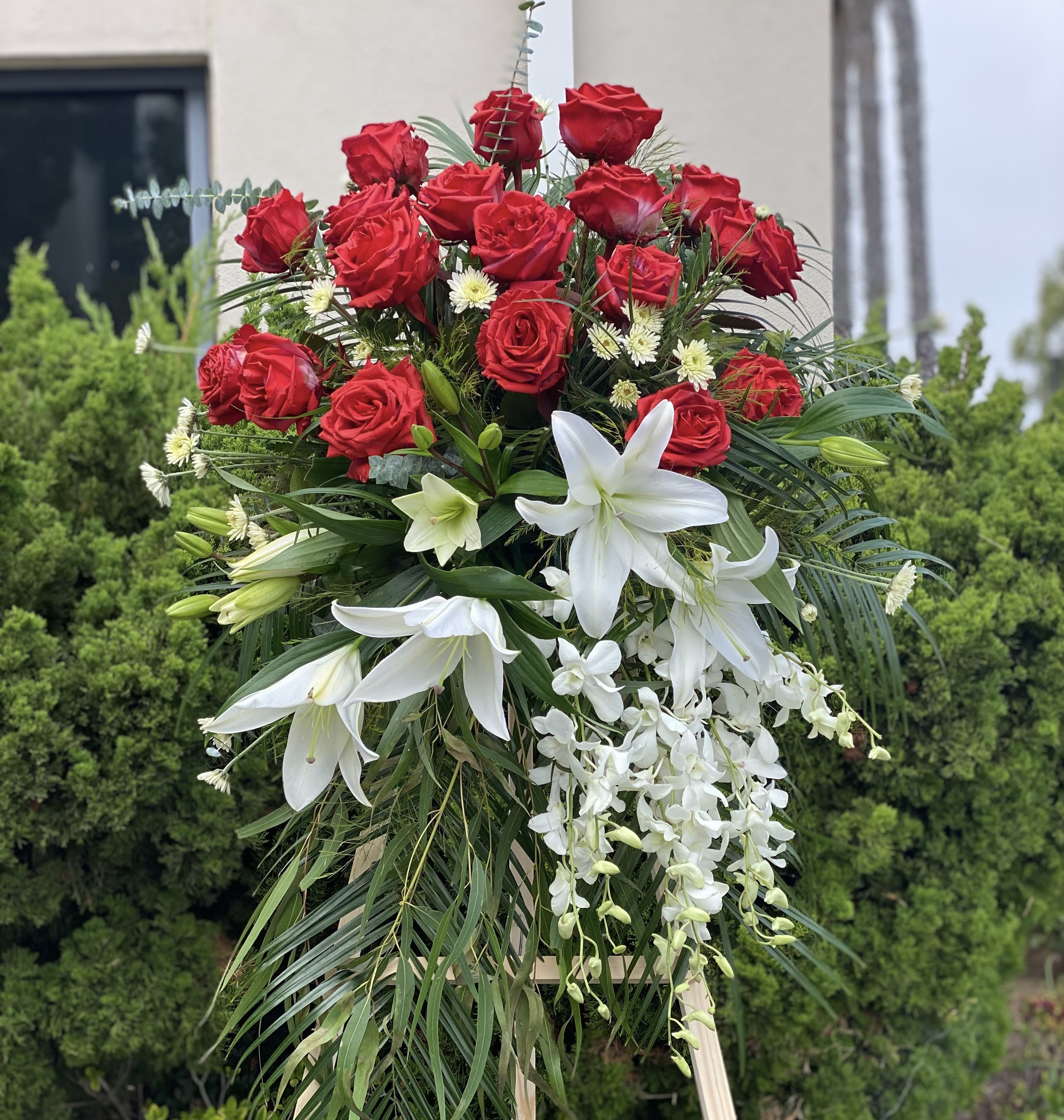 Standing floral spray with red roses, white lilies, and white orchids