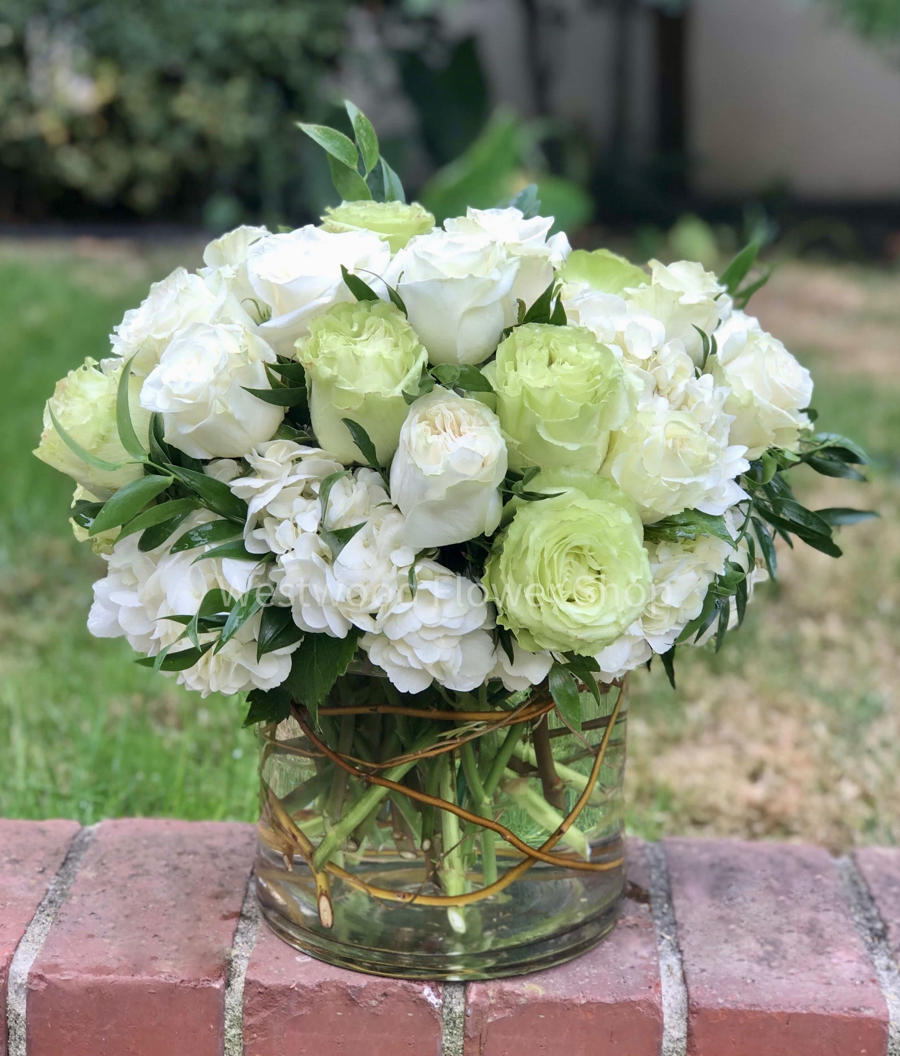 White and pale green roses arranged in a clear glass vase