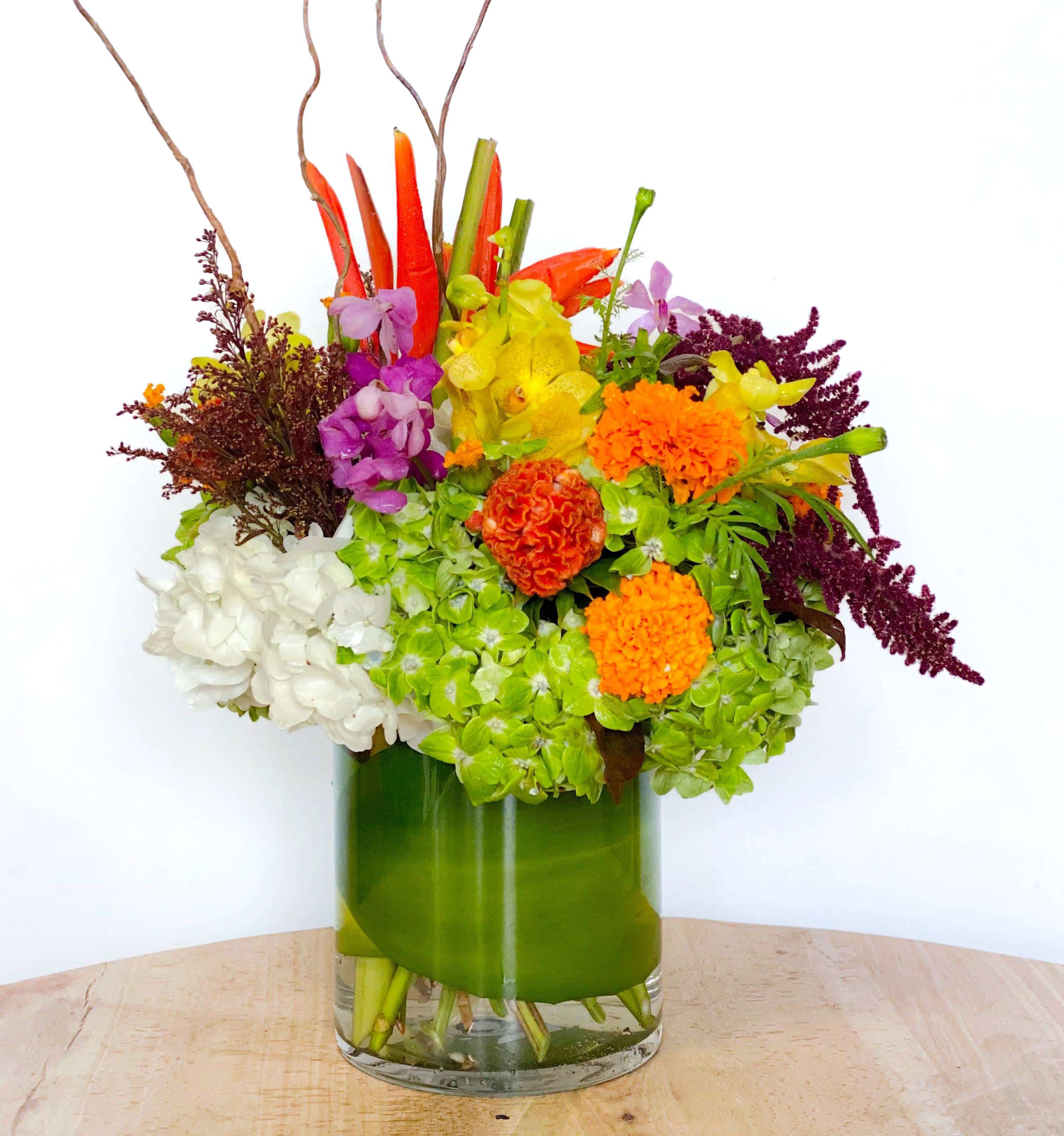 Colorful mixed flower arrangement in a green glass vase
