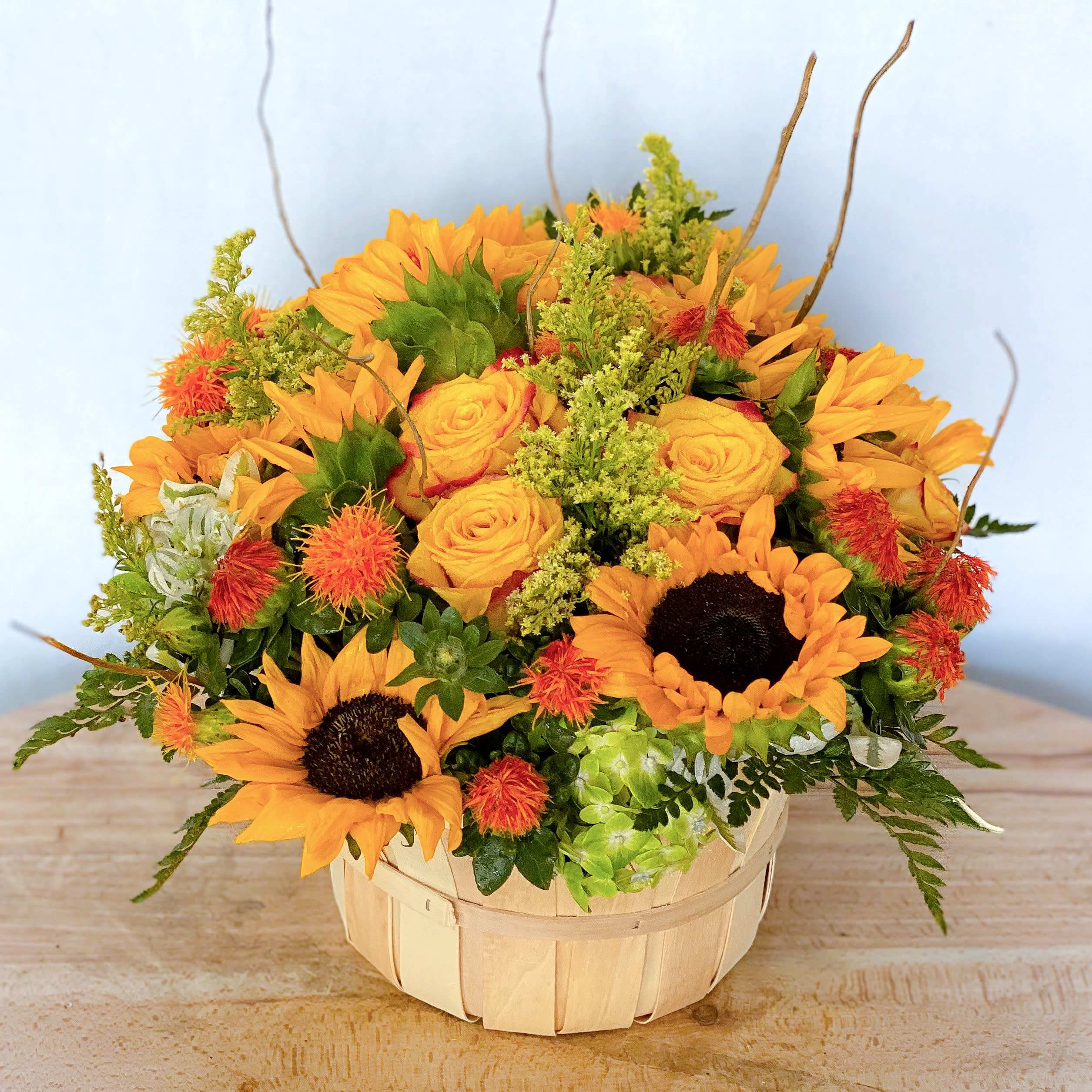 Basket of sunflowers and yellow roses with orange accents