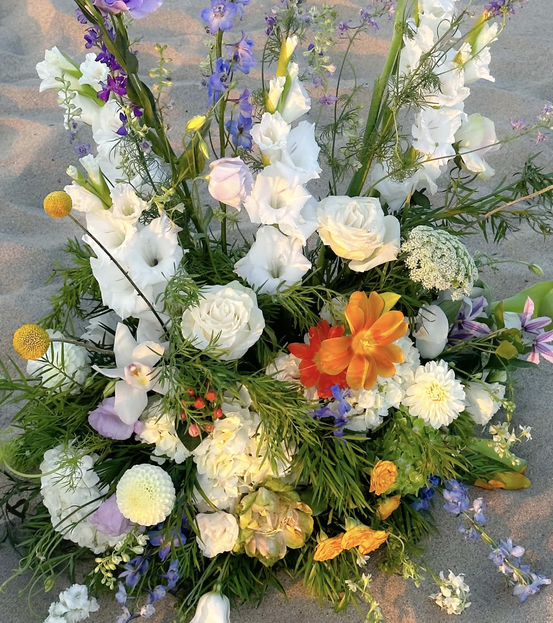 Large mixed floral arrangement with white, purple, and orange blooms