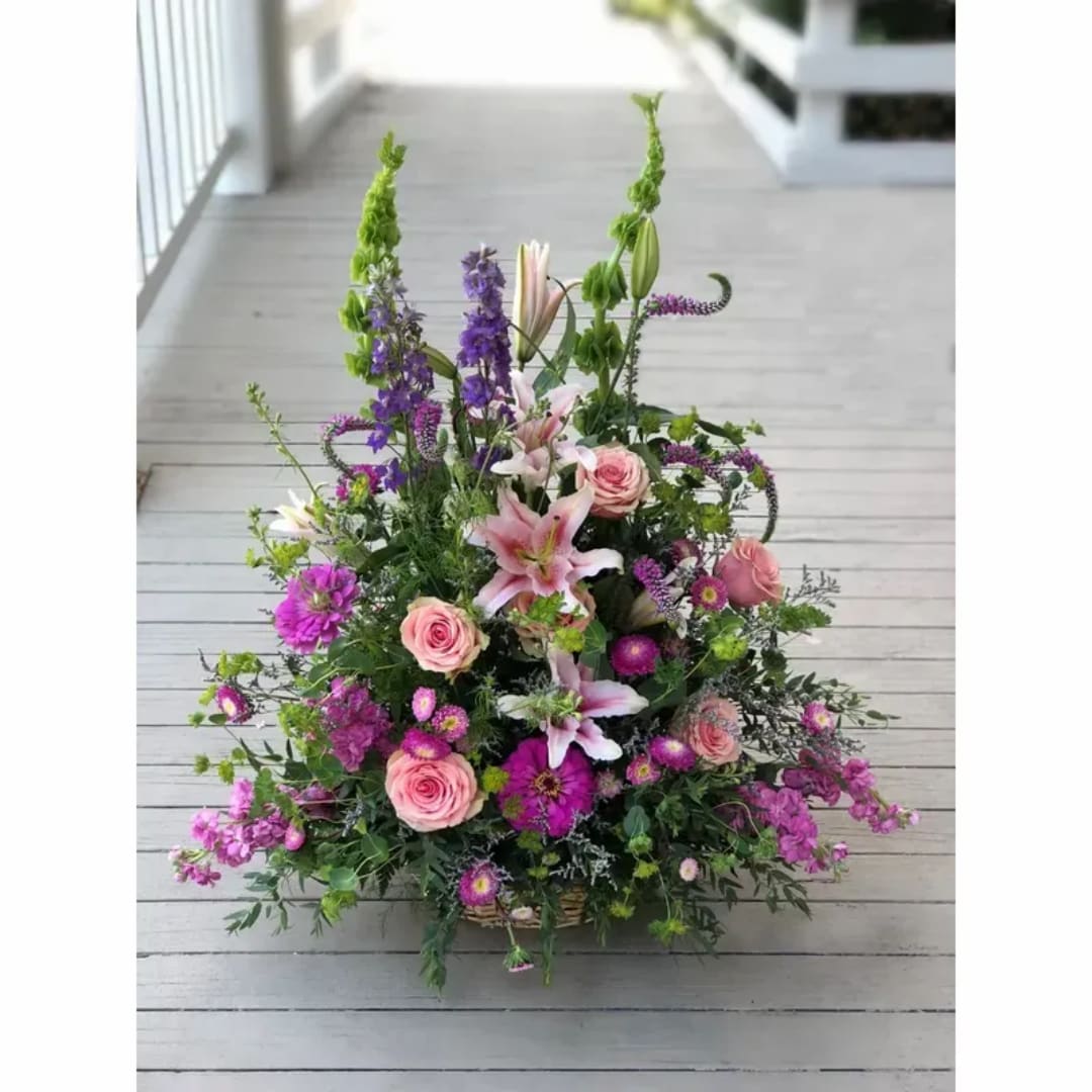 Large mixed bouquet with pink roses, lilies, and purple flowers in a basket