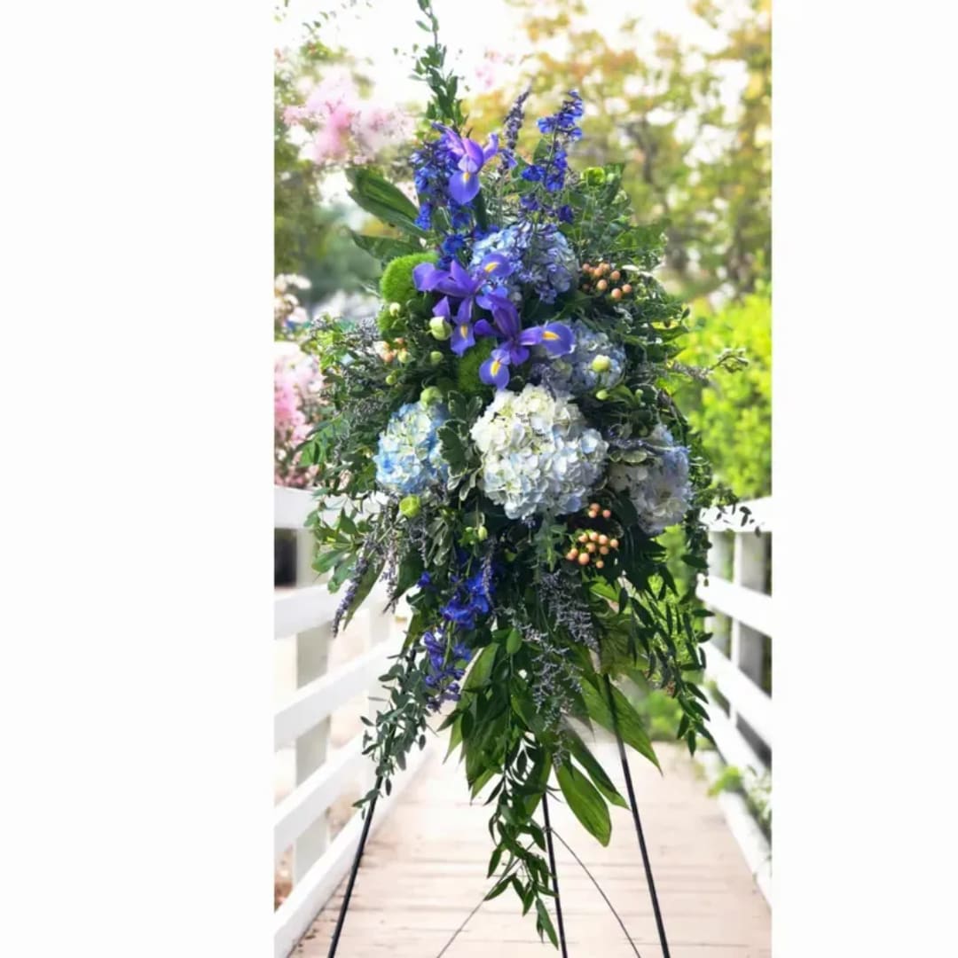 Tall blue and white floral arrangement on a stand outdoors