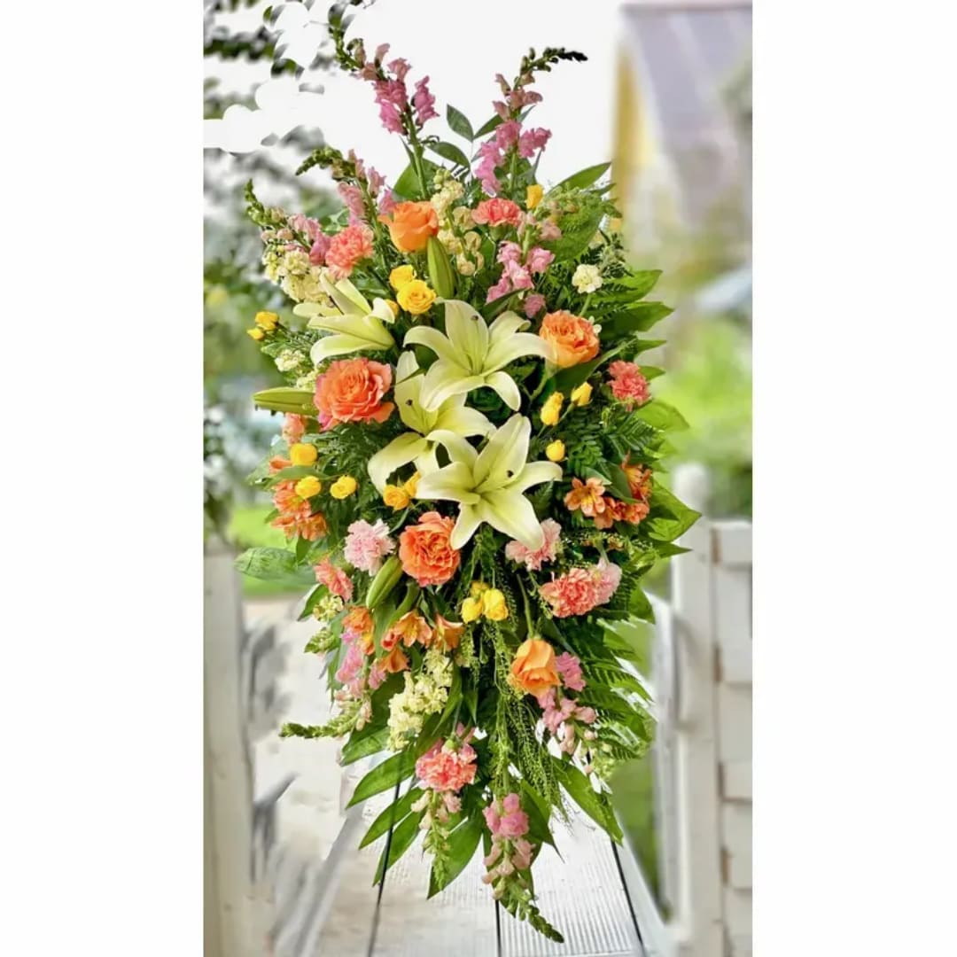 Tall floral standing spray with lilies, roses, and pink blooms