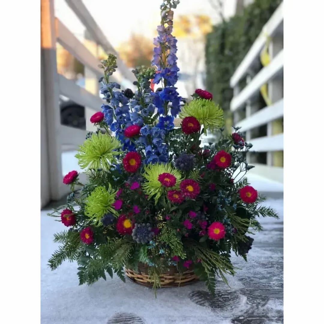 Colorful flower arrangement in a woven basket with tall blue blooms and bright pink flowers