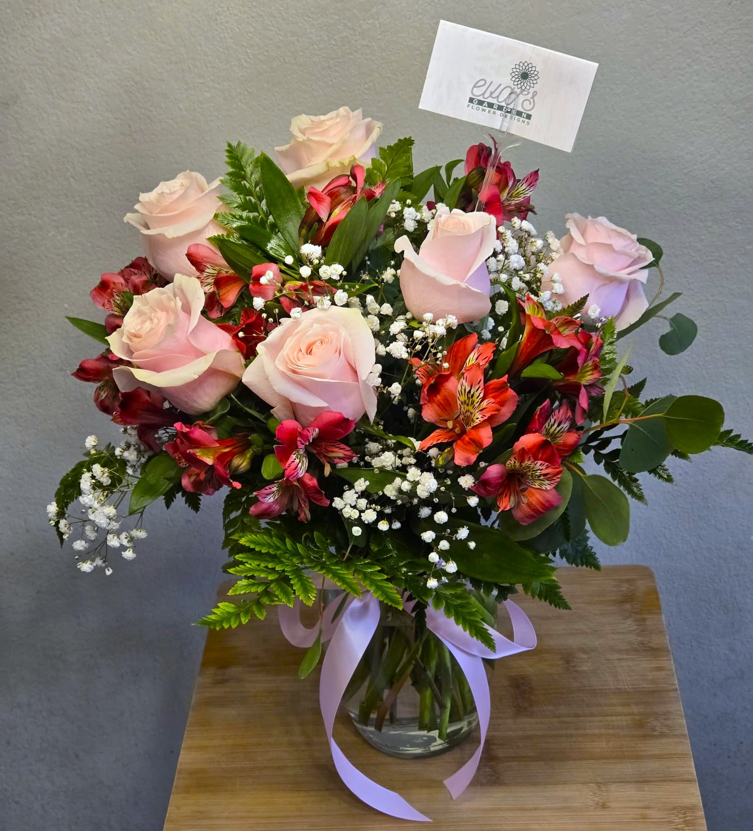 Bouquet of pale pink roses and red alstroemeria in a glass vase