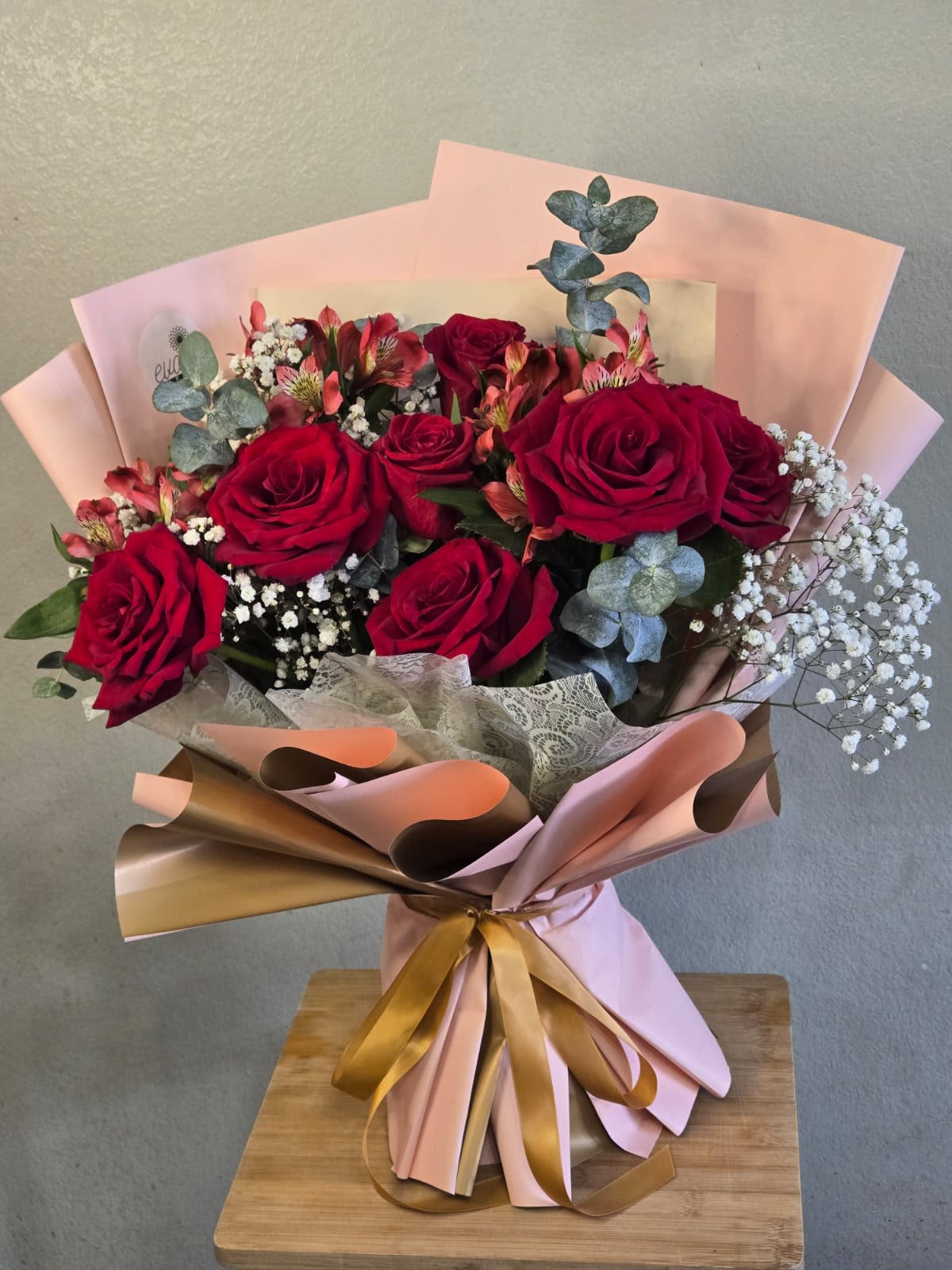 Bouquet of red roses with baby’s breath and pink wrapping