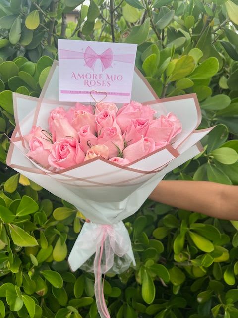 Bouquet of pink roses wrapped in white paper with a pink ribbon