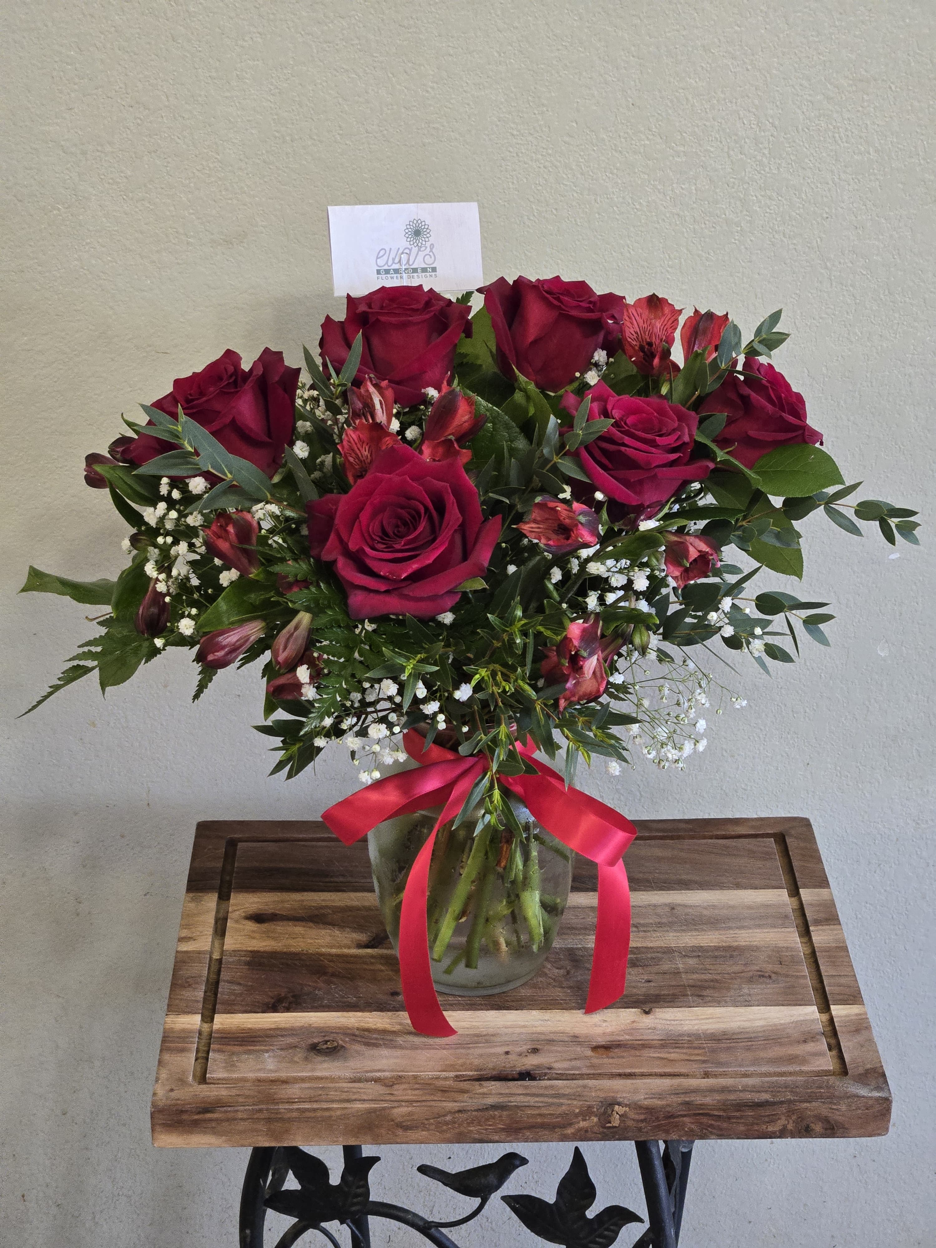 Bouquet of deep red roses and pink alstroemeria in a glass vase with a ribbon