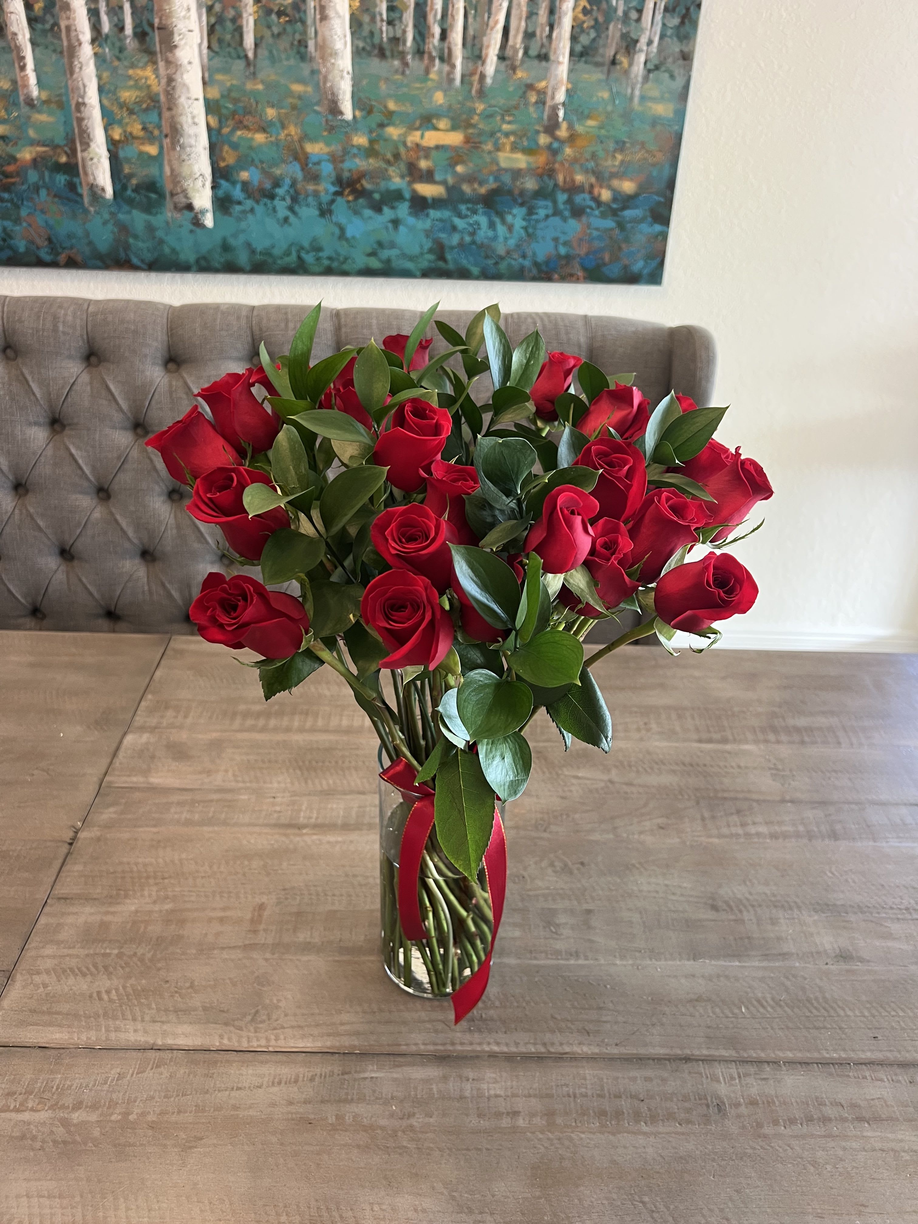 Red roses in a clear glass vase with a red ribbon