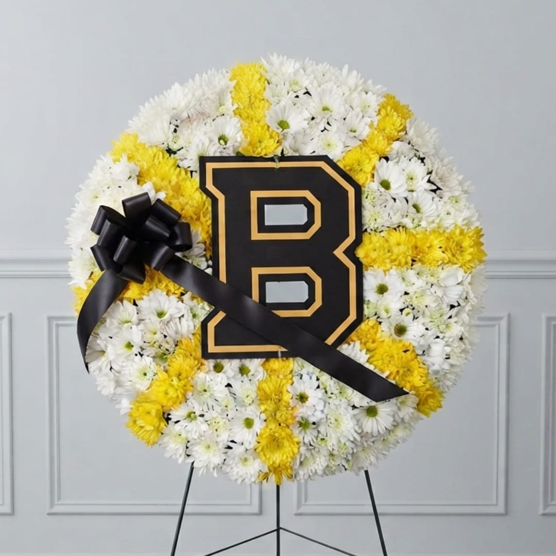 Round floral wreath of white and yellow daisies with a black letter B and ribbon