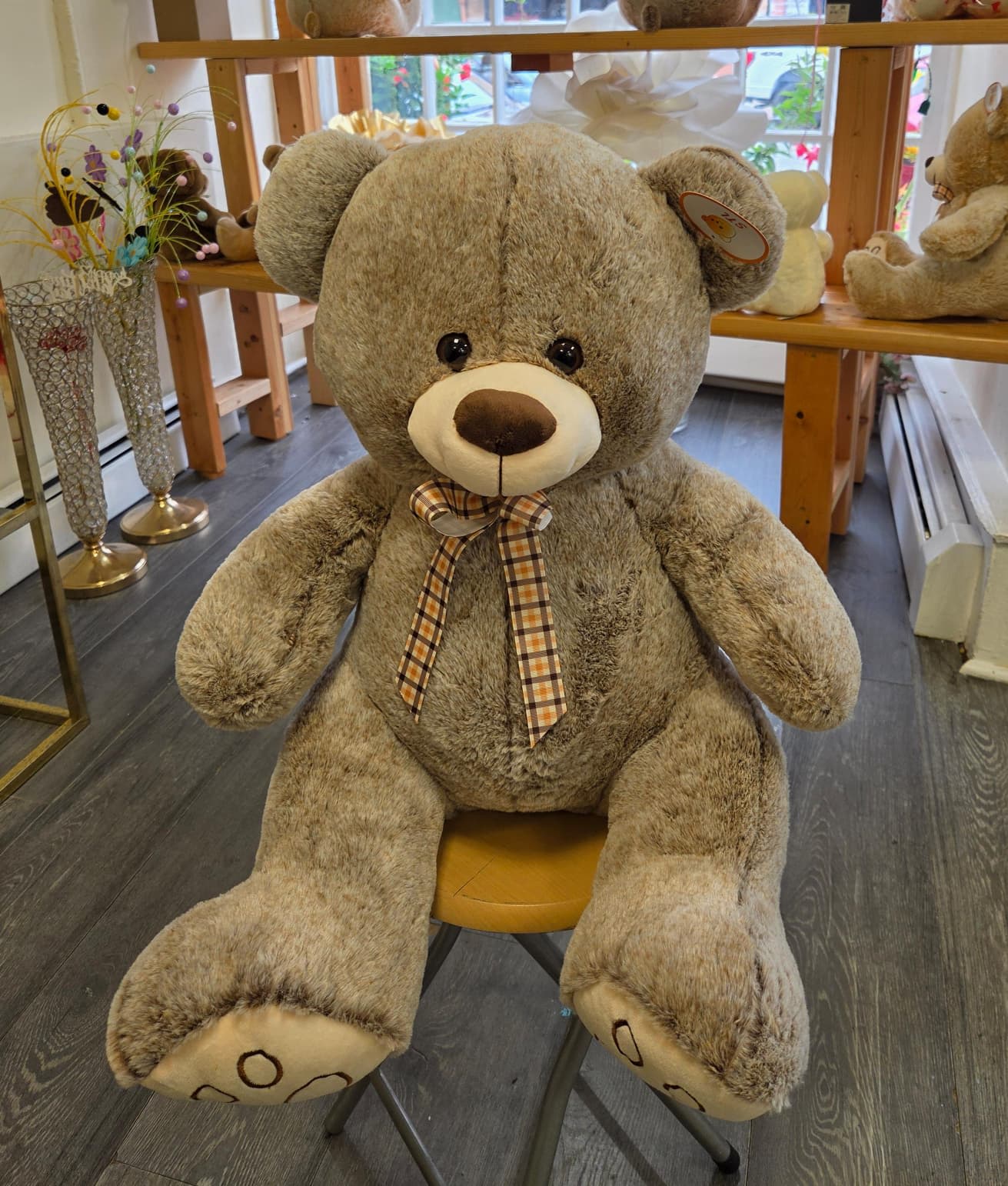Large plush teddy bear with a plaid ribbon bow