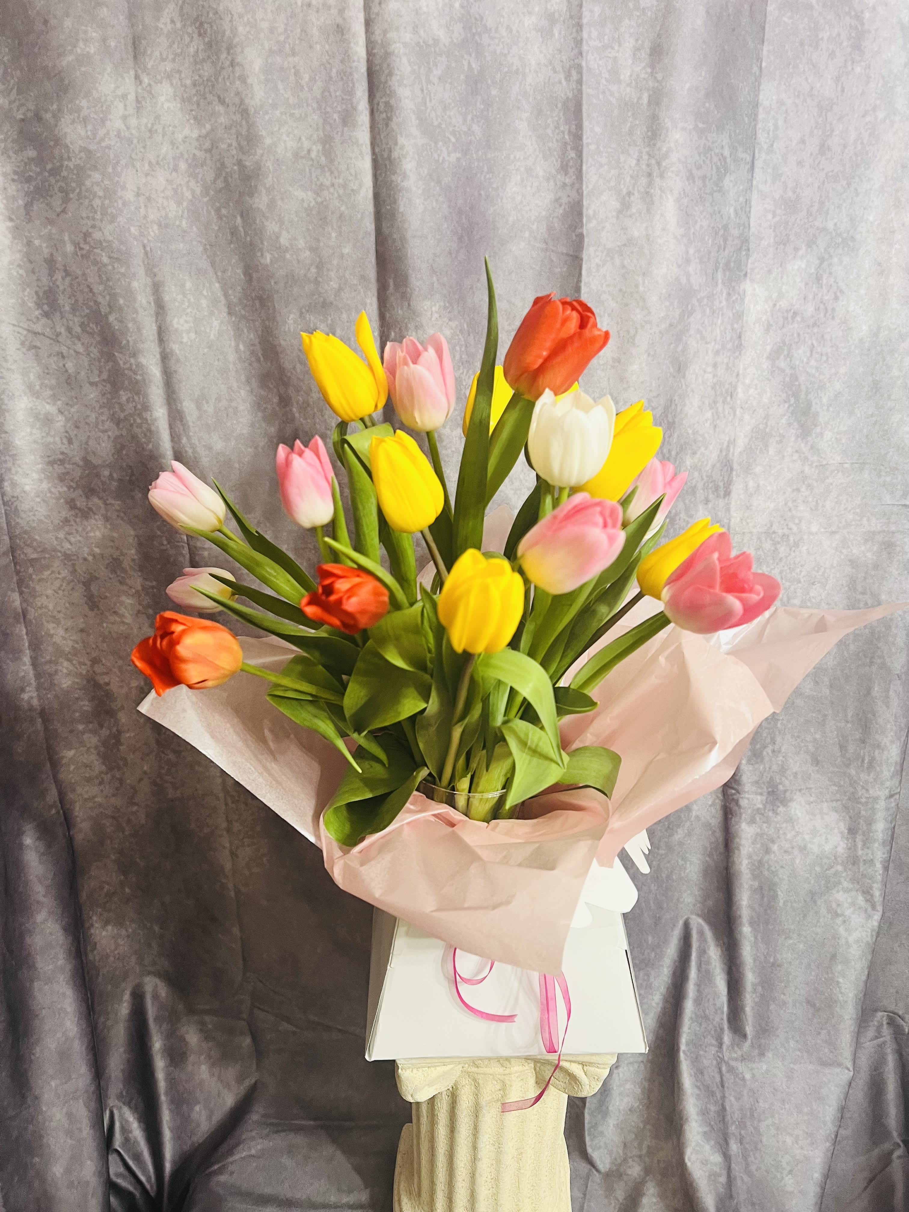 Bouquet of multicolored tulips wrapped in pink paper