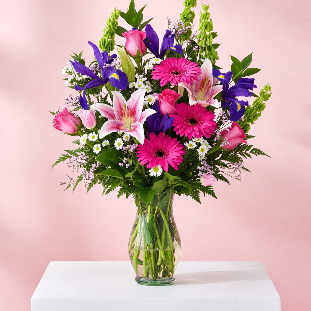 Mixed bouquet of pink, purple, and white flowers in a clear glass vase
