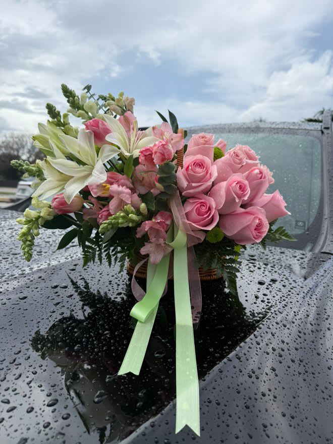 Pink rose and lily bouquet with ribbon on a car hood