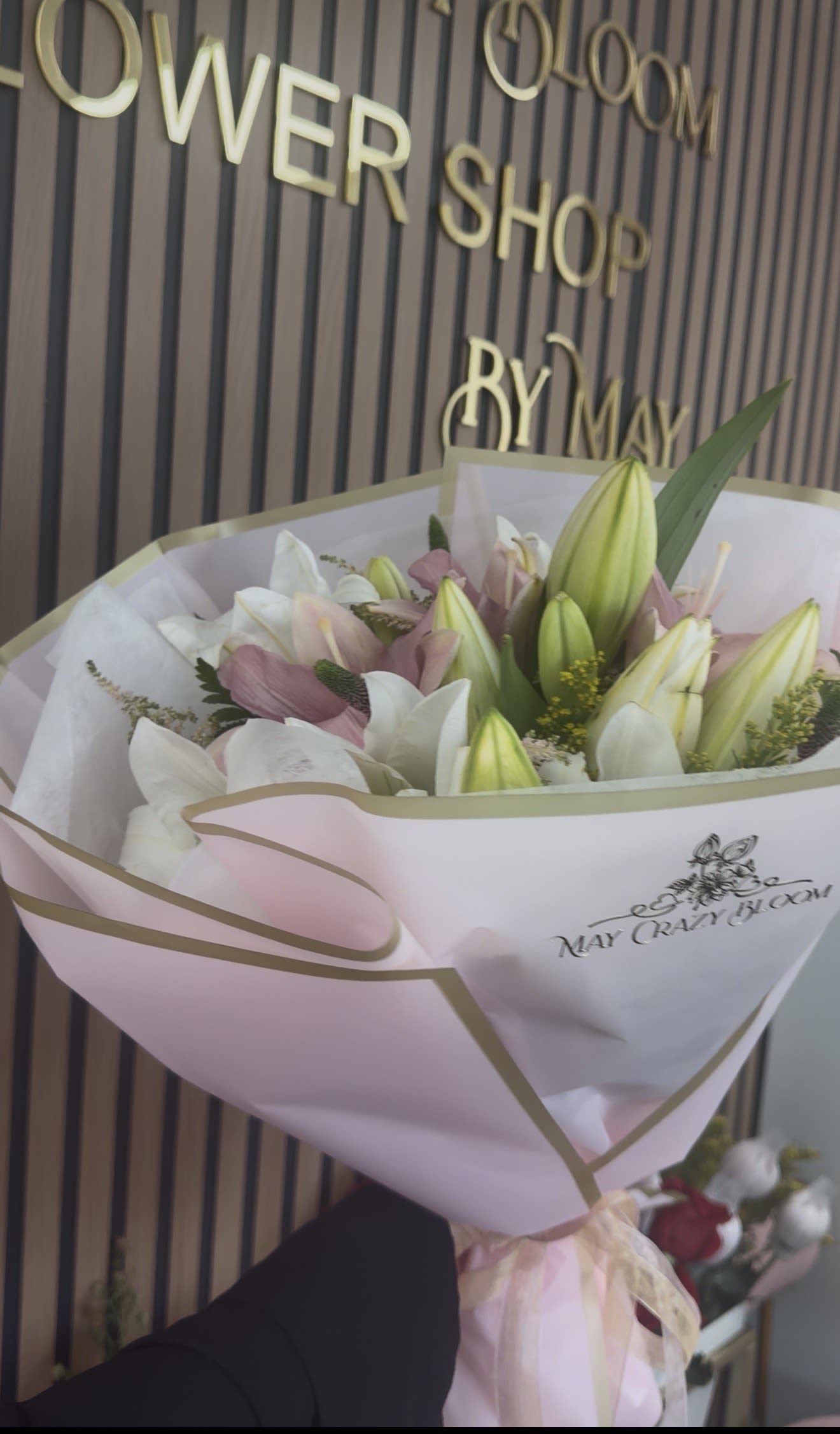 Lilies Lovers - Soft white and blush-pink lilies take center stage in this Lily Lovers bouquet, the perfect birthday bouquet or anniversary flowers for someone who loves understated romance. Unopened green lily buds add vertical texture and a fresh-spring lift so the recipient will feel truly celebrated the moment they unwrap it.  Hand-tied and wrapped in pale pink and white paper with gold edging, the arrangement reads polished and gift-ready; a ribbon and bouquet wrap finish the look. Colors: pink, white, green. The rounded presentation balances open blooms and buds for lasting visual interest and a graceful silhouette.  Ideal as a thoughtful thank-you, everyday gift, or anniversary surprise, these lilies offer a soft, feminine mood that suits many occasions. Keep stems in fresh water, recut if needed, and enjoy several days of fragrant, elegant blooms.