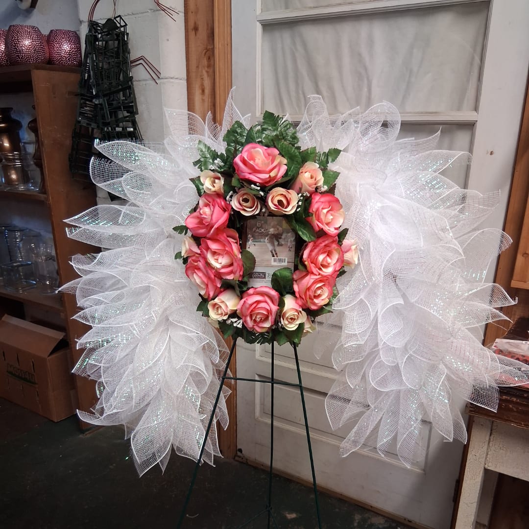 Pink rose wreath with white mesh ribbon on a metal stand