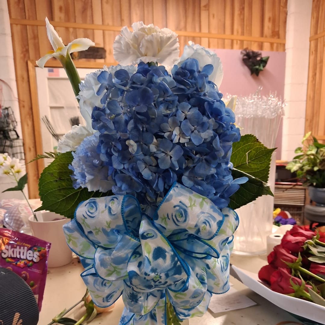 Blue hydrangea arrangement with white flowers and a patterned ribbon bow