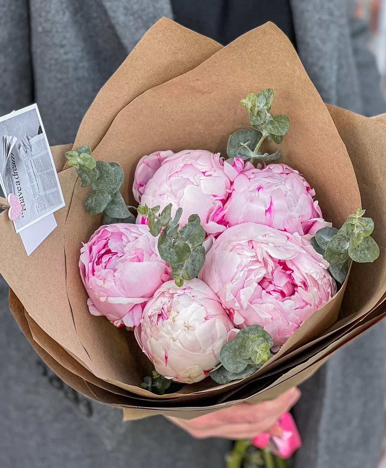 Bouquet of pale pink peonies wrapped in brown paper