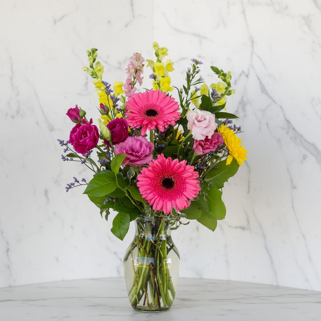 Pink gerbera daisies and mixed flowers in a glass vase