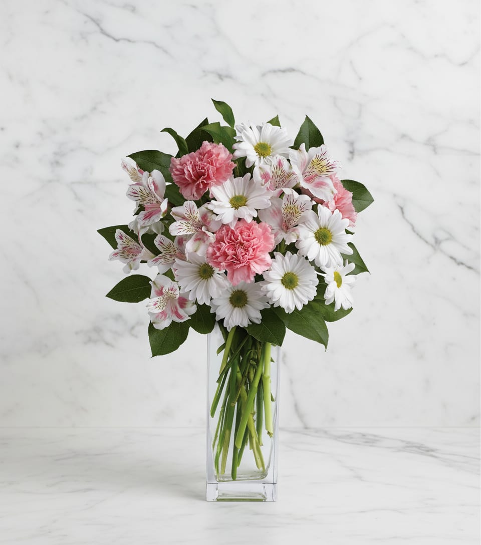 Pink carnations and white daisies in a clear glass vase