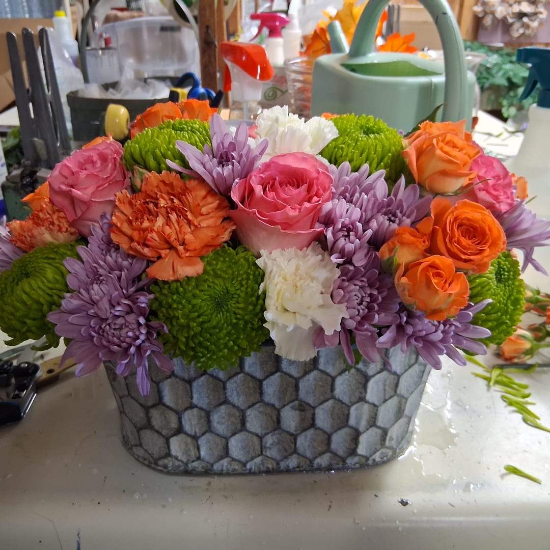 Mixed bouquet of roses, chrysanthemums, and carnations in a patterned container