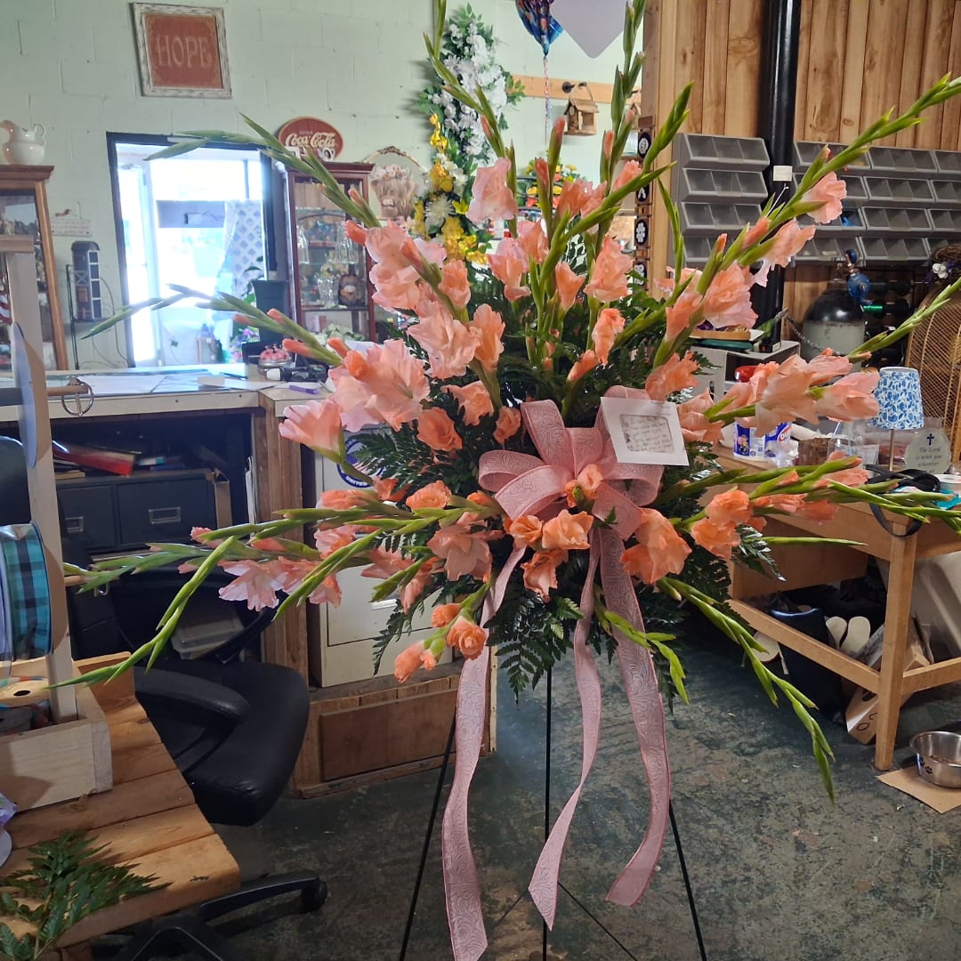 Large peach floral spray on a black stand with pink ribbon