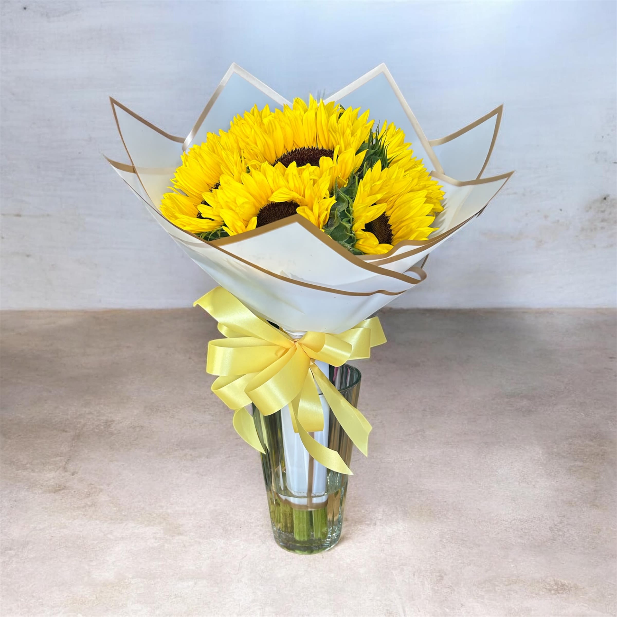 Bright Day Bouquet - Bright, bold, and full of sunshine, this hand-wrapped bouquet features 7 vibrant sunflowers beautifully arranged to make a cheerful statement. Each bloom showcases rich golden petals and deep centers, creating a warm and uplifting feel. Finished with fresh greenery and wrapped with care, this bouquet is perfect for brightening someone’s day.  Ideal for birthdays, celebrations, or just because, the “Golden Seven” is a simple yet stunning expression of happiness and positivity.