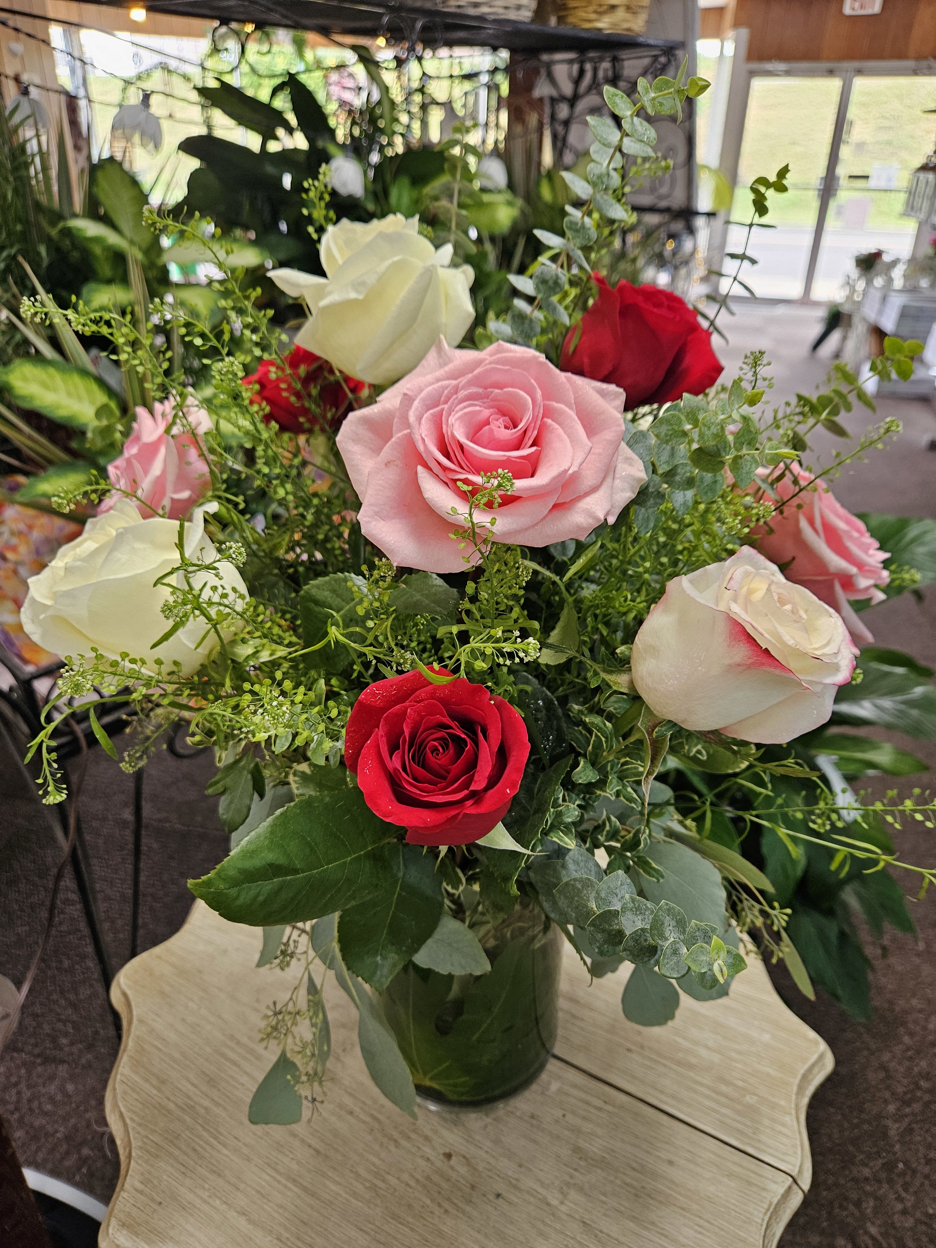 Arrangement of pink, red, and white roses in a clear glass vase